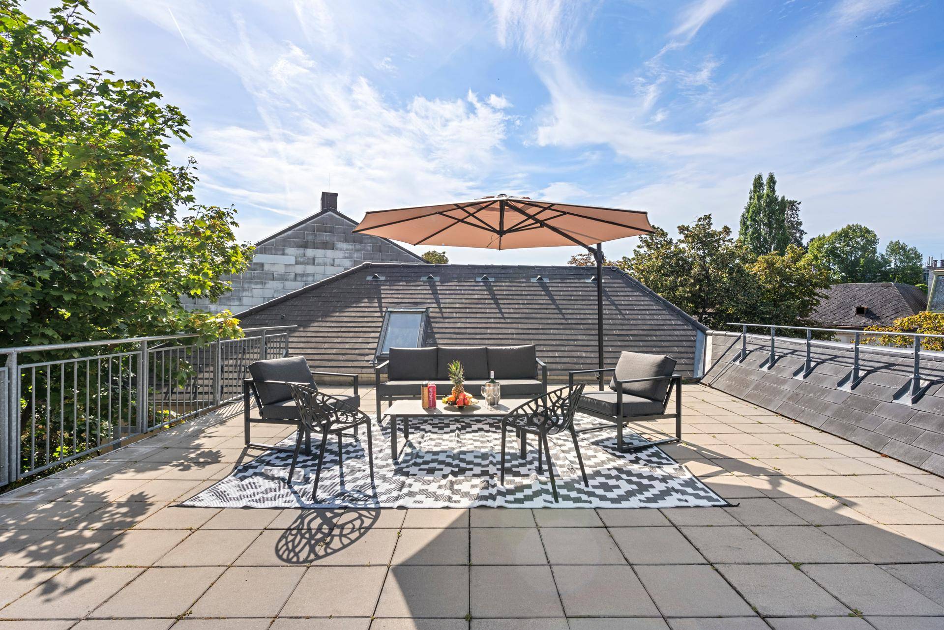 Sonnige Dachterrasse mit Lounge-Möbeln und Blick über die umliegenden Dächer.