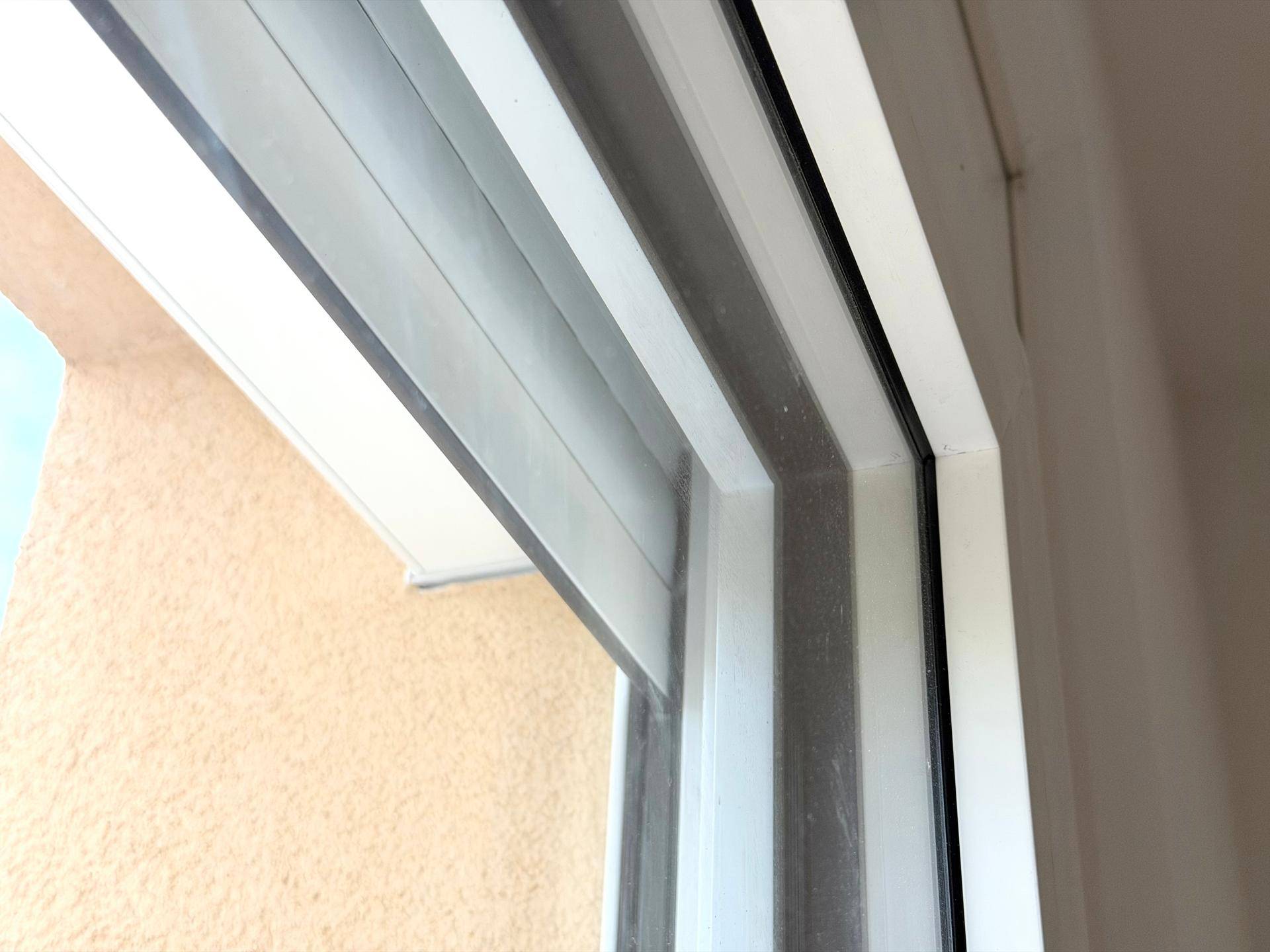 Detailansicht eines Fensterrahmens und der strukturierten Außenwand des Gebäudes.