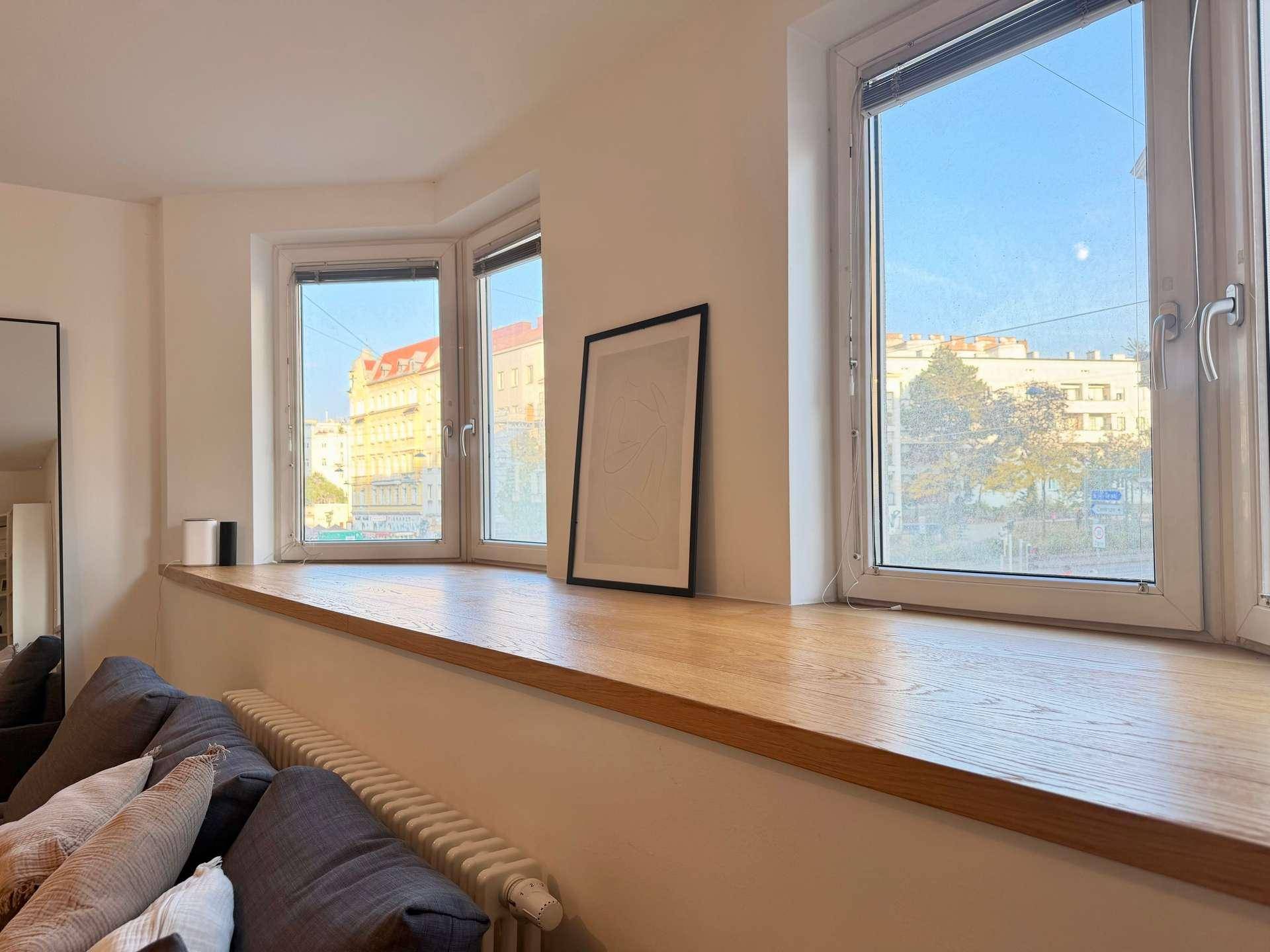 Große Fensterfront mit Holzfensterbank und Heizkörper im Wohnzimmer.