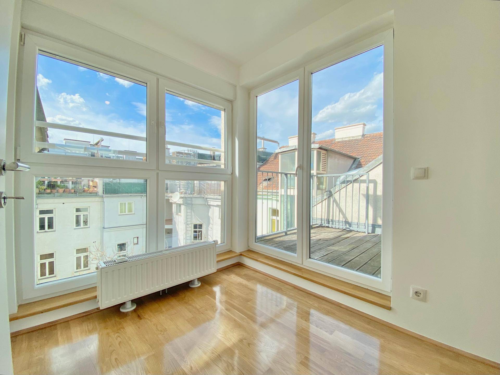 Heller Raum mit großen Fenstern, die viel Tageslicht hereinlassen und einen Stadtblick bieten.