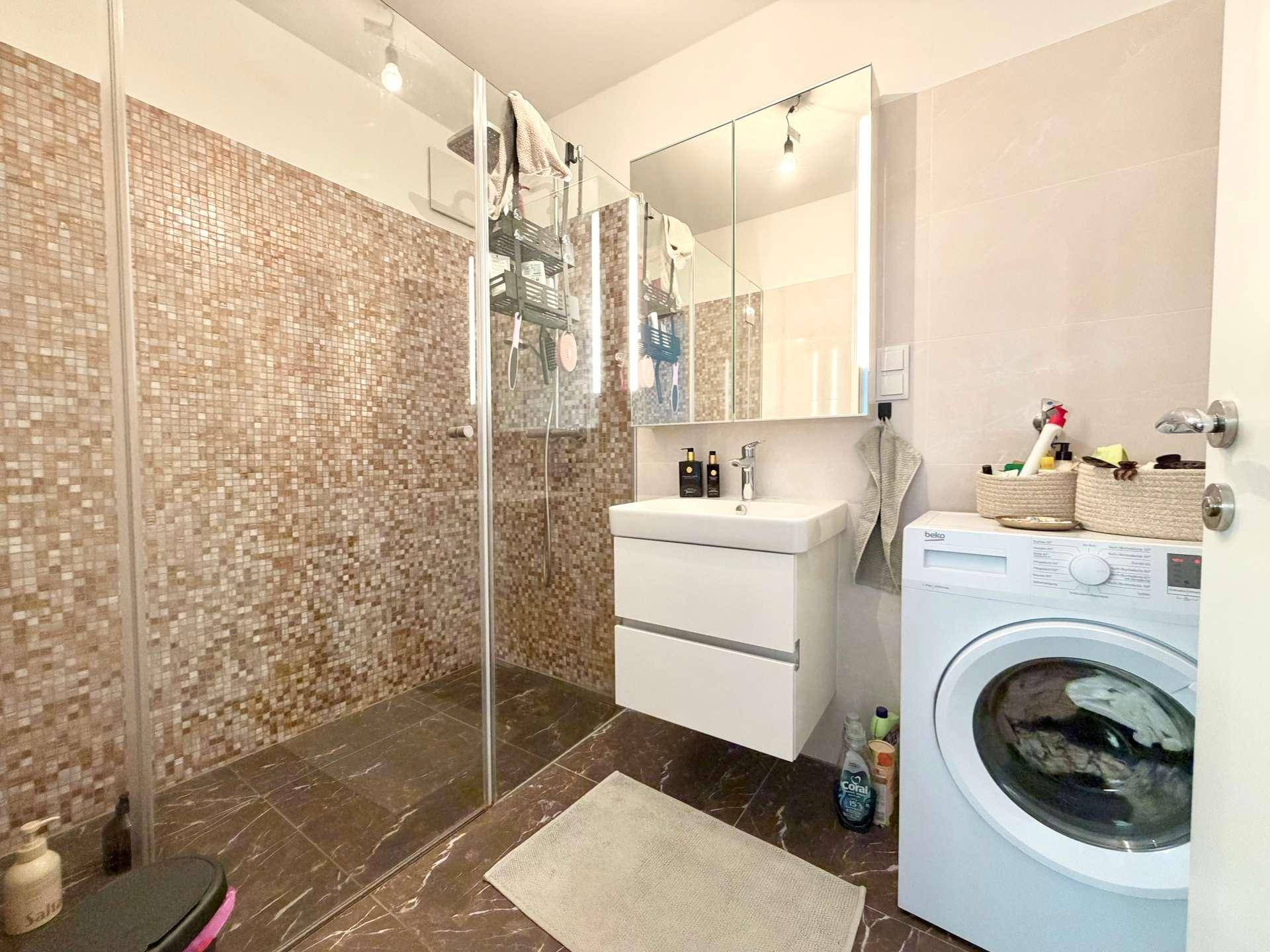 Modernes Badezimmer mit ebenerdiger Dusche, Waschbecken und Waschmaschine.