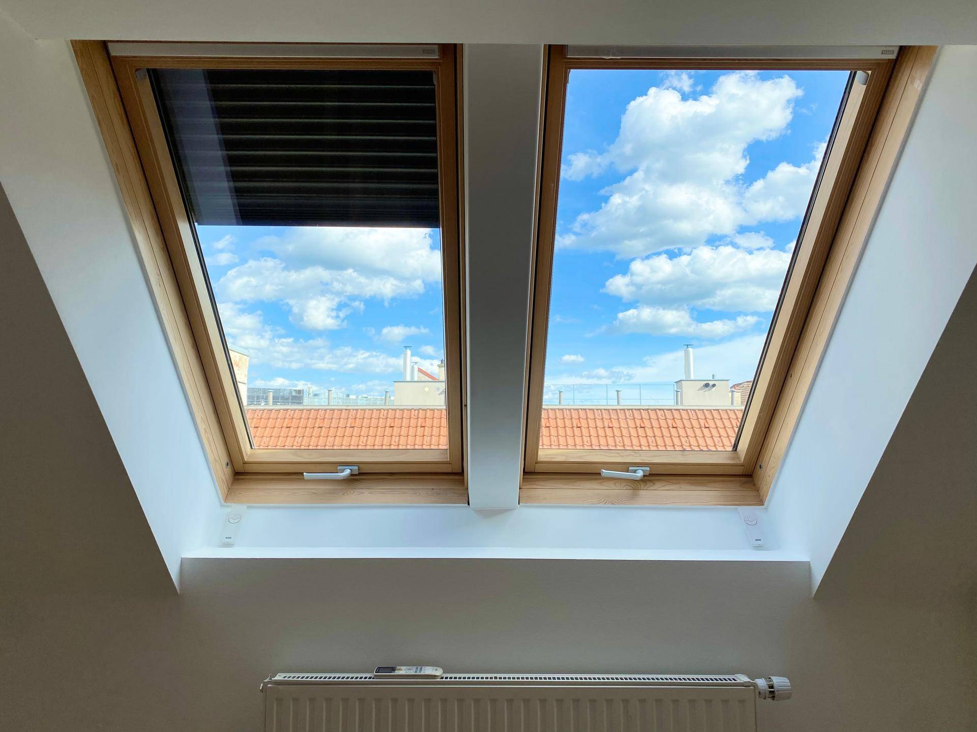 Zwei Dachfenster bieten einen hellen Ausblick auf die umliegenden Dächer und den Himmel.
