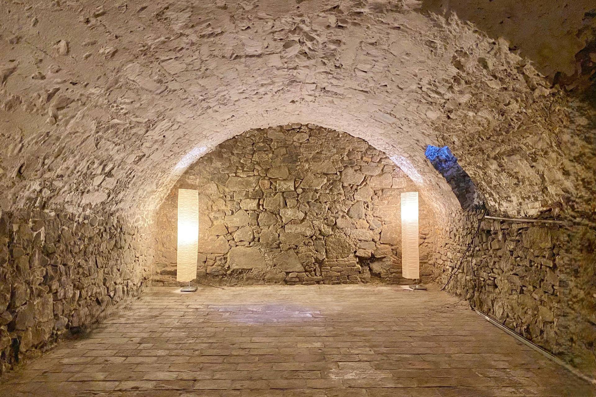 Historischer Gewölbekeller mit freiliegenden Steinmauern und stimmungsvoller Beleuchtung.