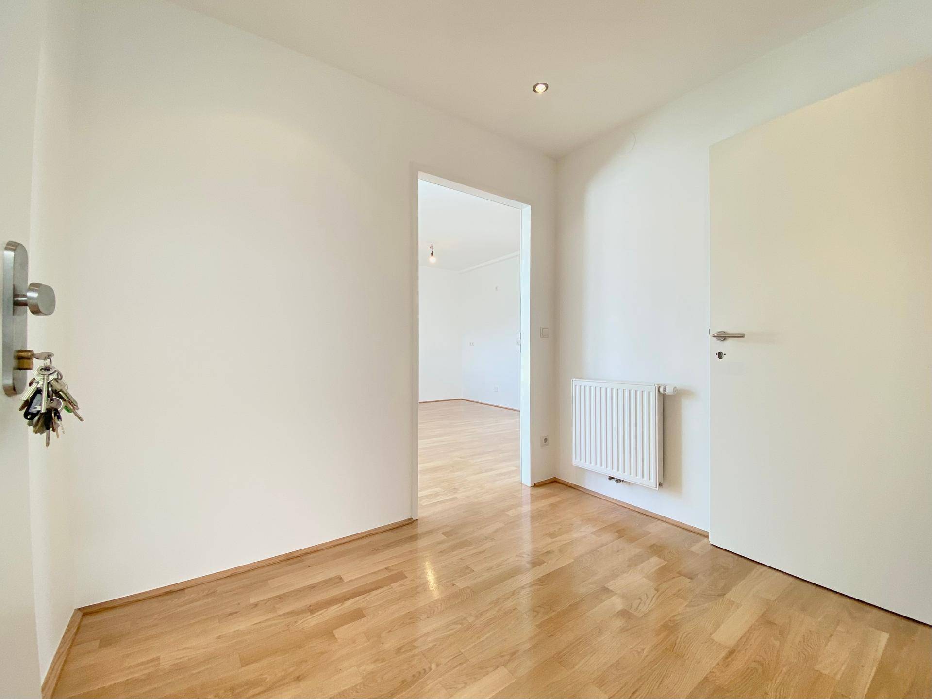 Eingangsbereich mit hellem Parkettboden und Zugang zu weiteren Räumen der Wohnung.