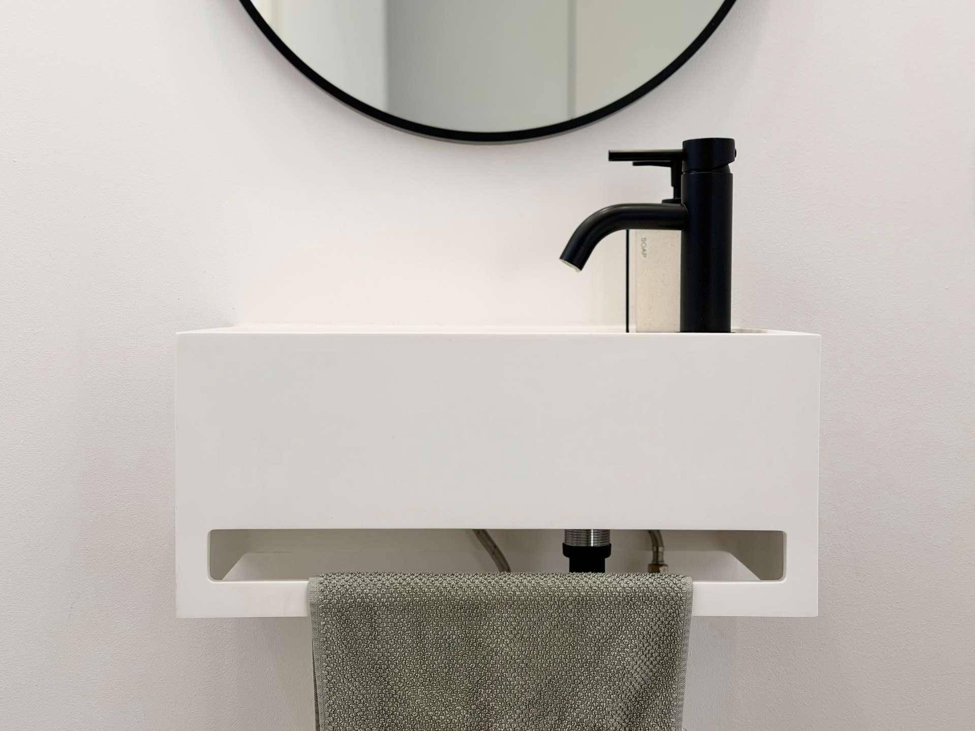Nahaufnahme des modernen Waschbeckens mit schwarzem Wasserhahn im Gäste-WC.