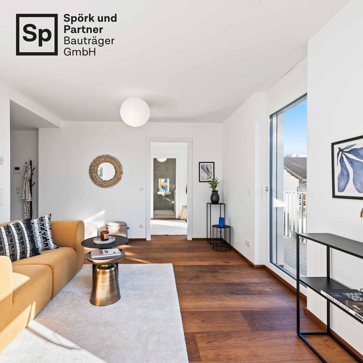 Helles Wohnzimmer mit Holzboden, modernem Sofa und Blick in den angrenzenden Flur.