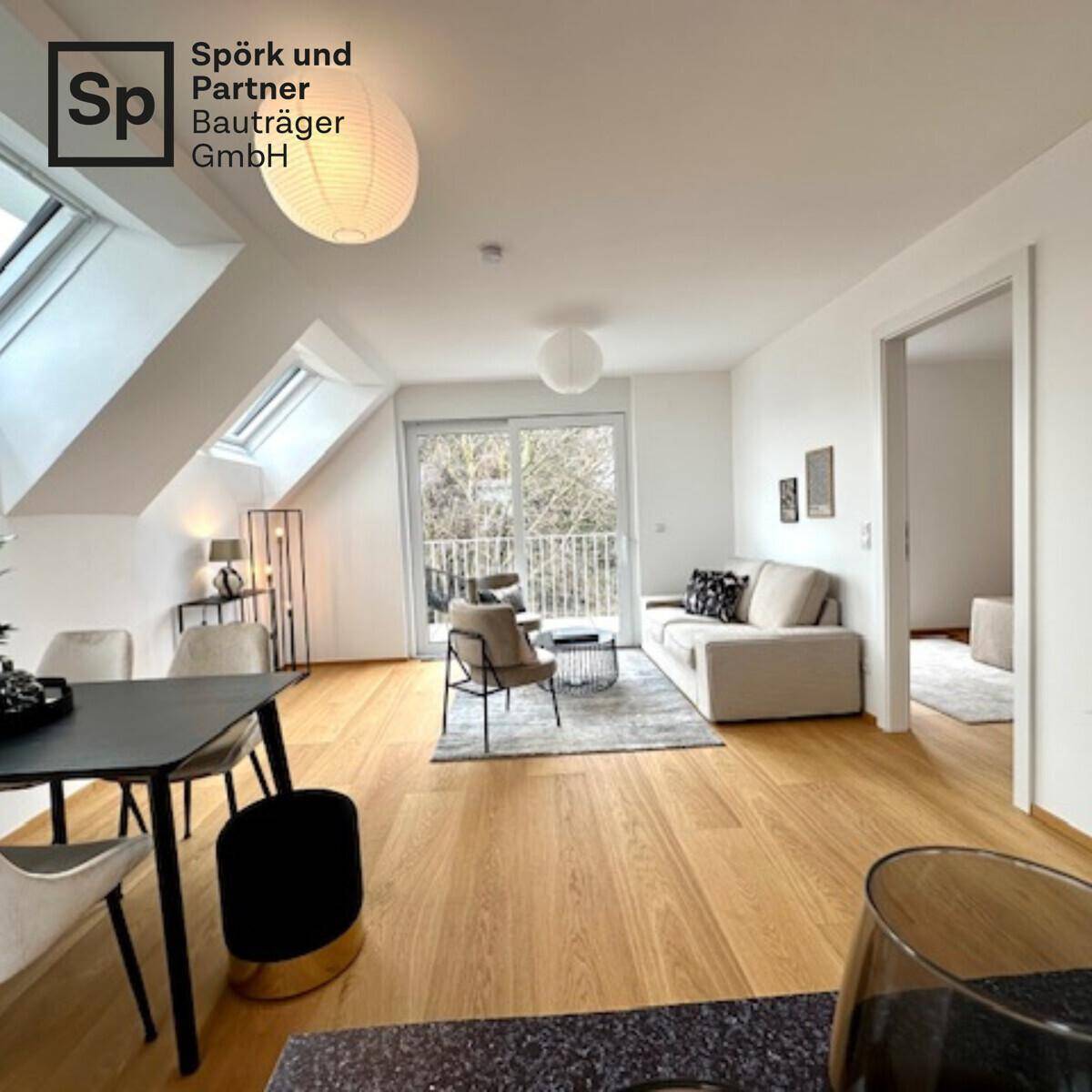 Heller offener Wohn- und Essbereich mit Holzboden, Dachfenstern und Zugang zum Balkon.