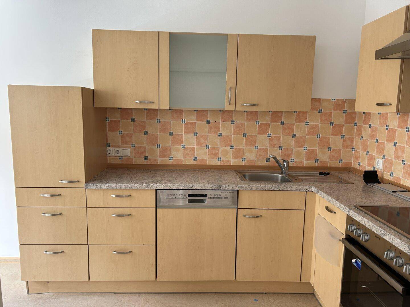 Funktionale Einbauküche mit hellen Holzfronten, Spülmaschine und gefliestem Fliesenspiegel.