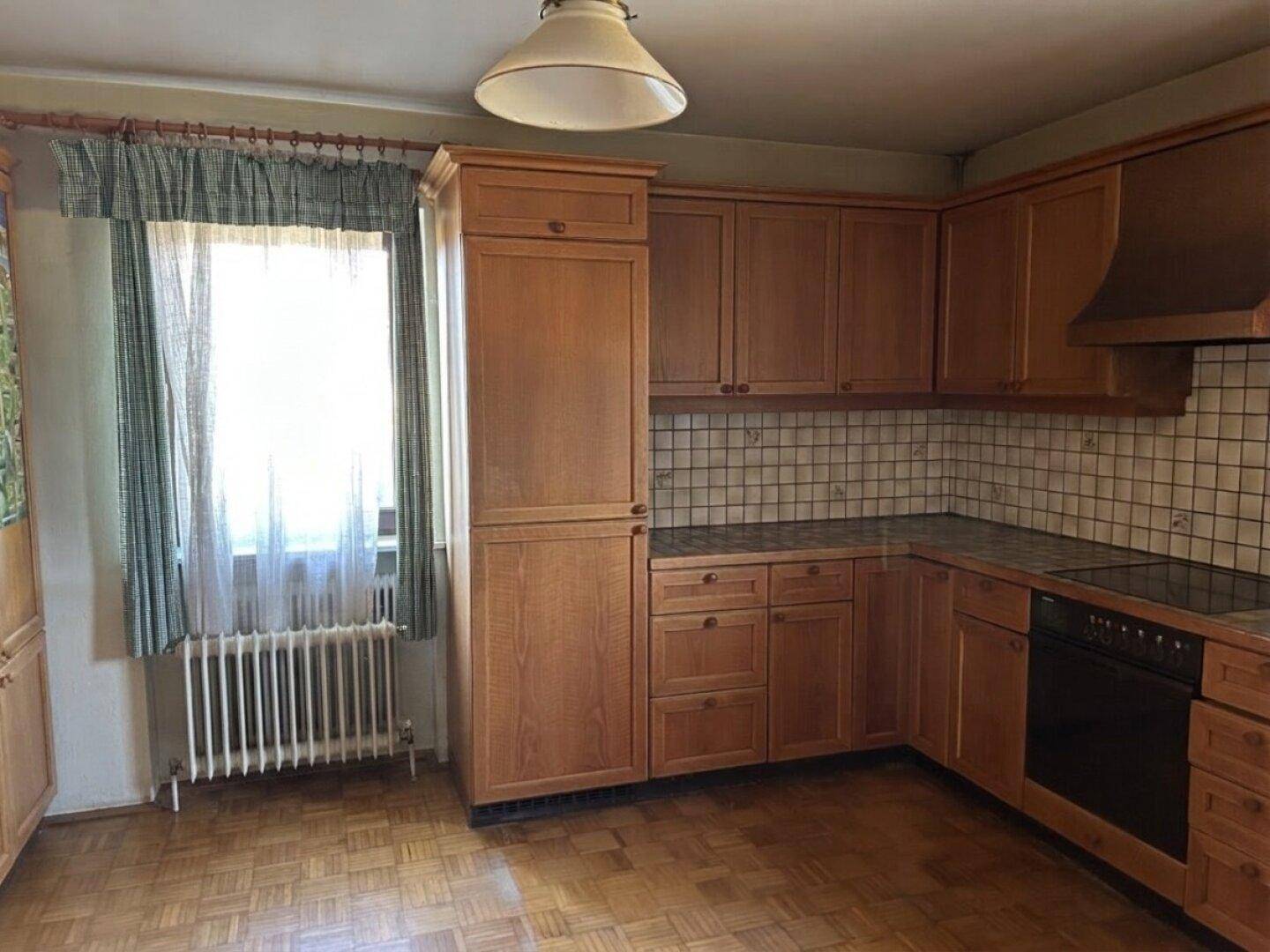 Geräumige Holzküche mit viel Stauraum, Fenster und Heizkörper, ideal für Familien.