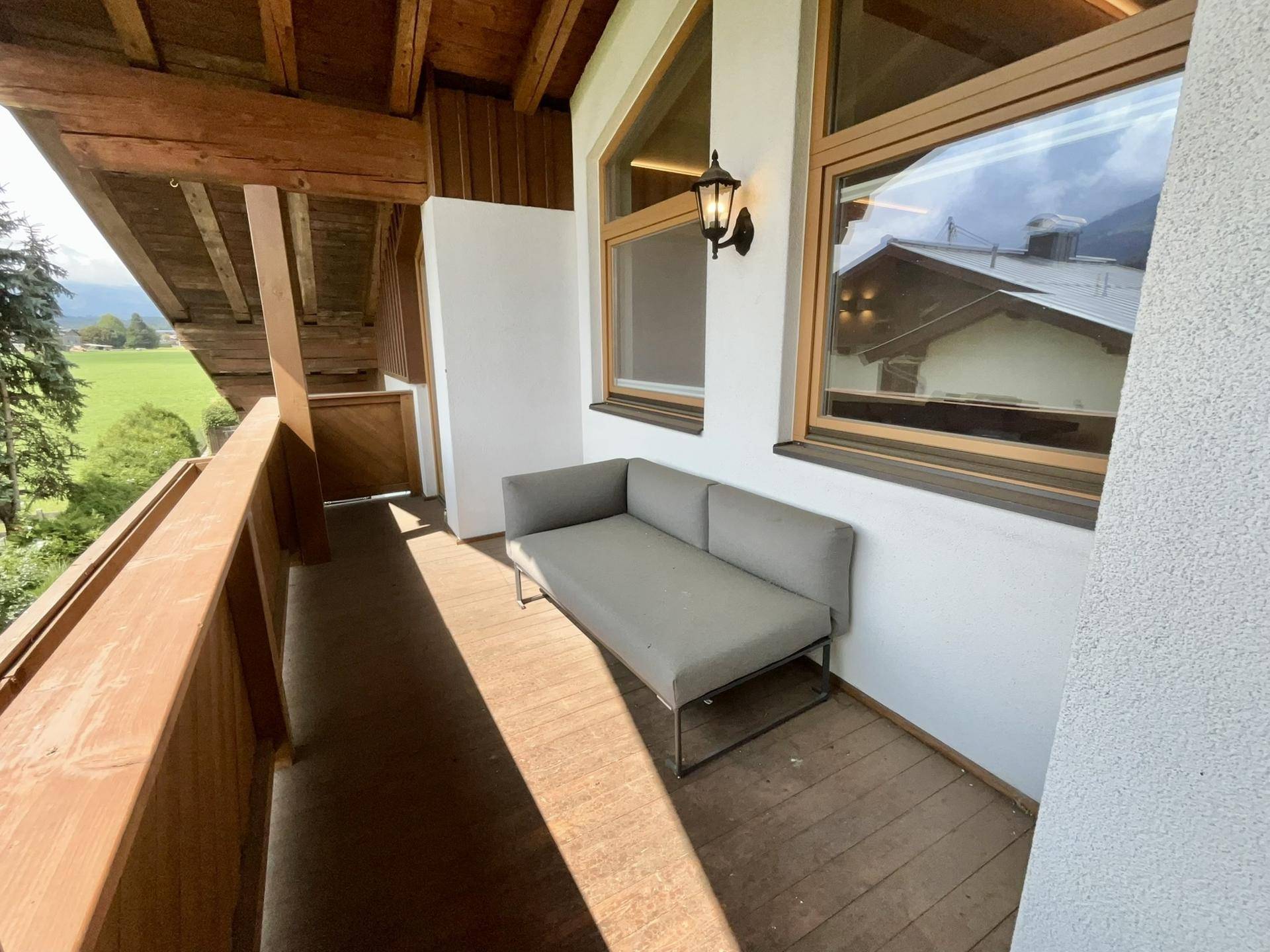 Gemütlicher Balkon mit Sitzgelegenheit und weitem Blick auf die grüne Landschaft und Berge.