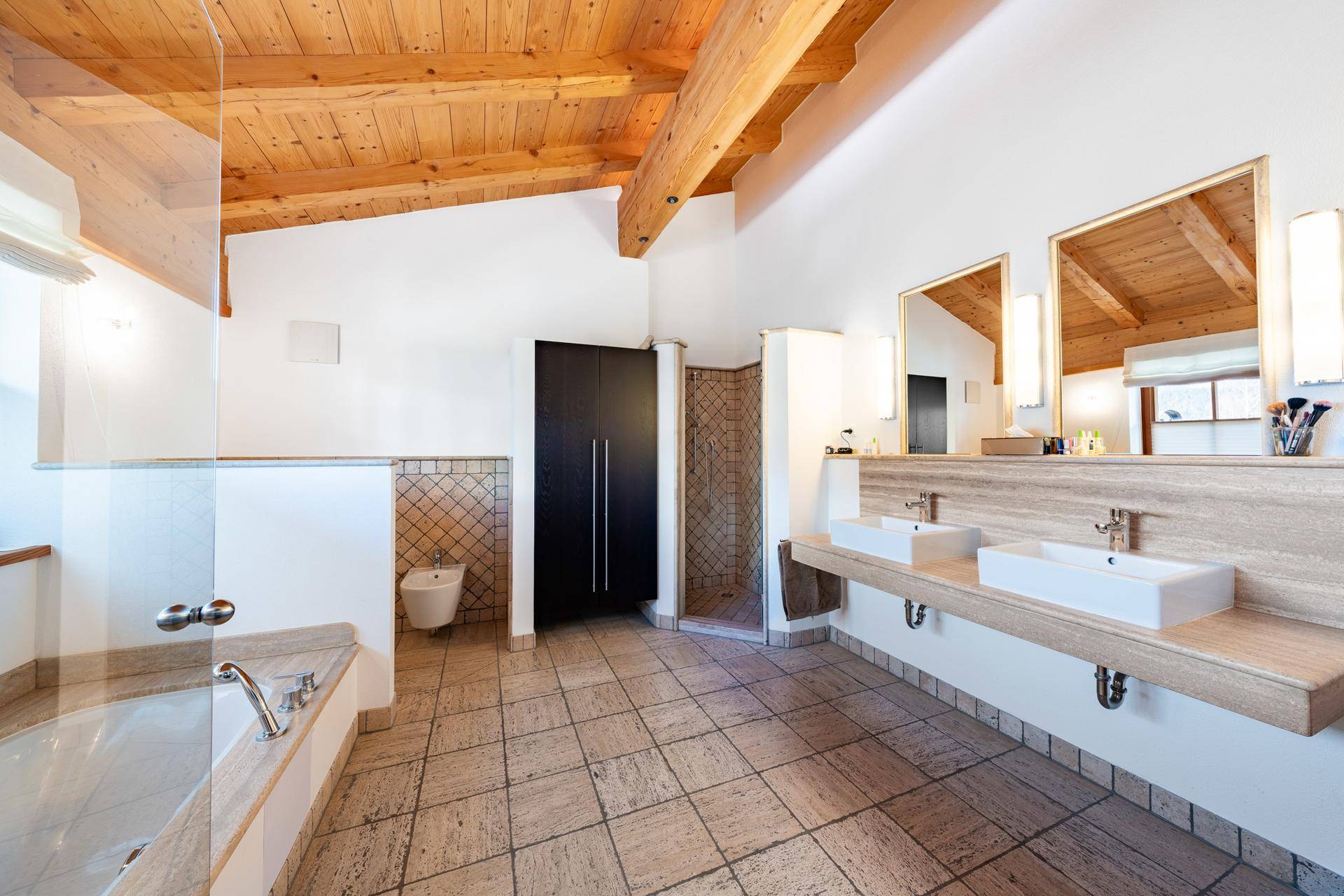 Geräumiges Badezimmer mit Doppelwaschbecken, Badewanne und Holzbalkendecke.