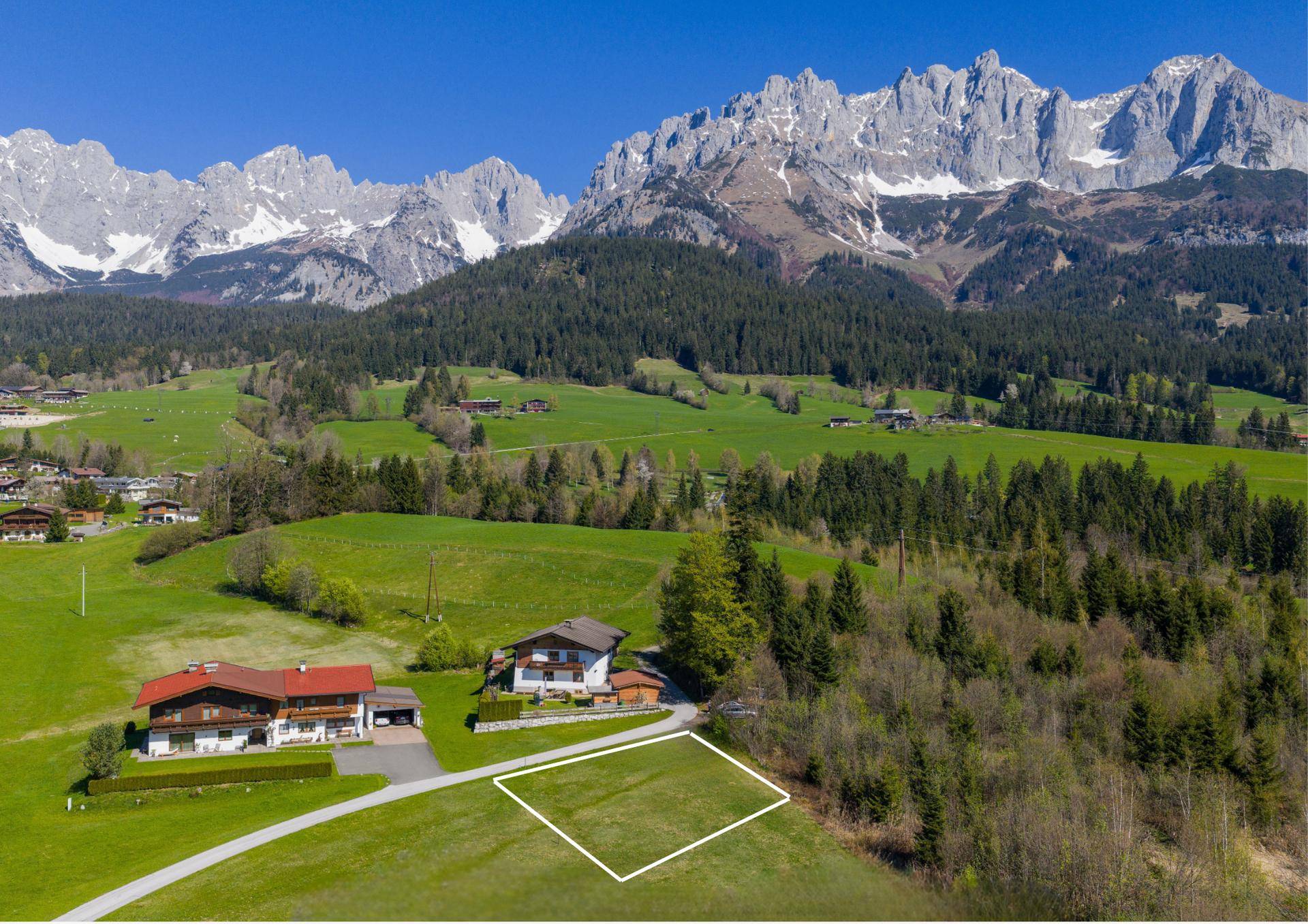 Luftaufnahme eines Grundstücks in ländlicher Umgebung mit Bergblick und umliegenden Häusern.