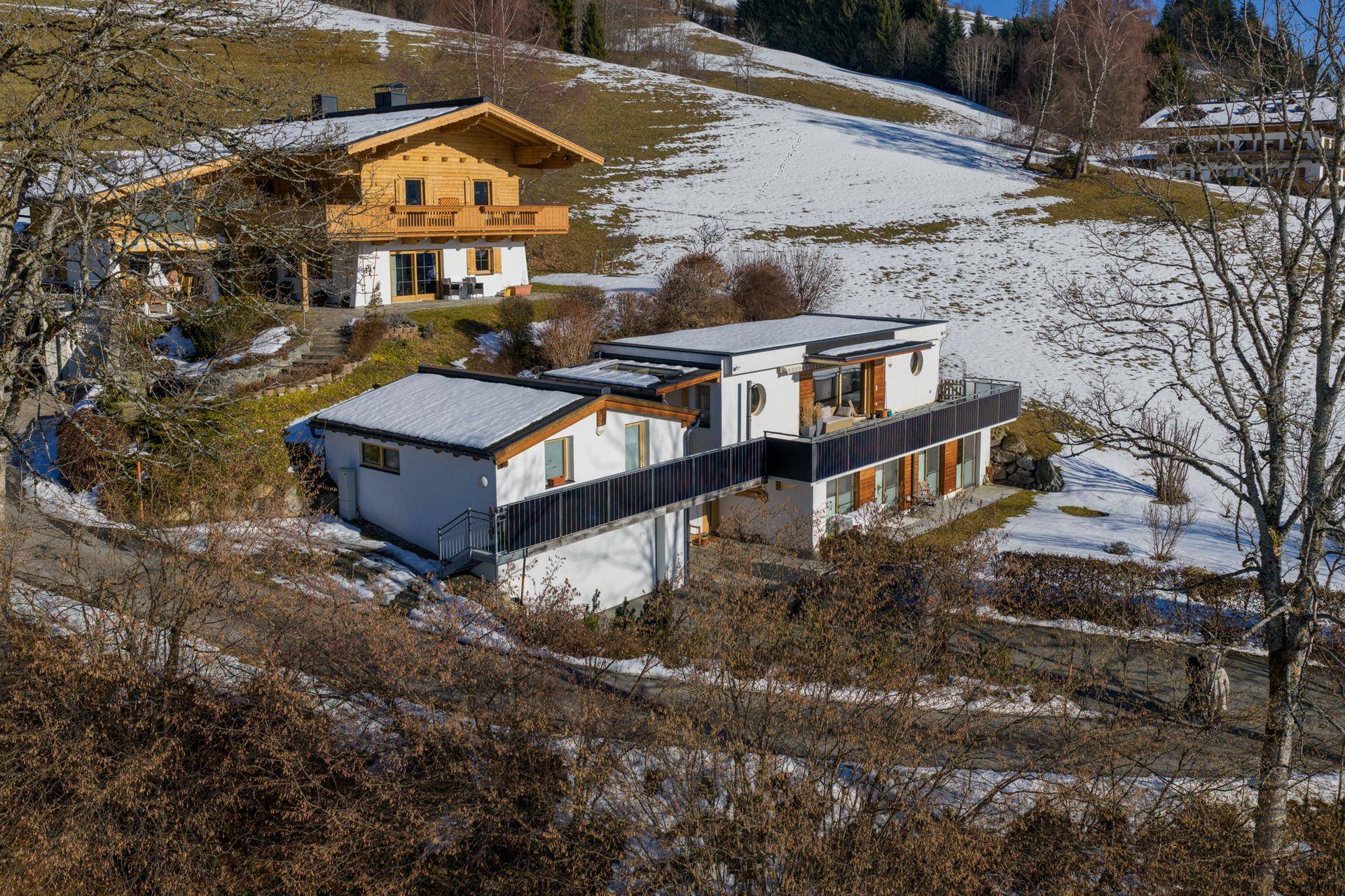 Ansicht des modernen Hauses mit mehreren Balkonen und der umliegenden verschneiten Landschaft.