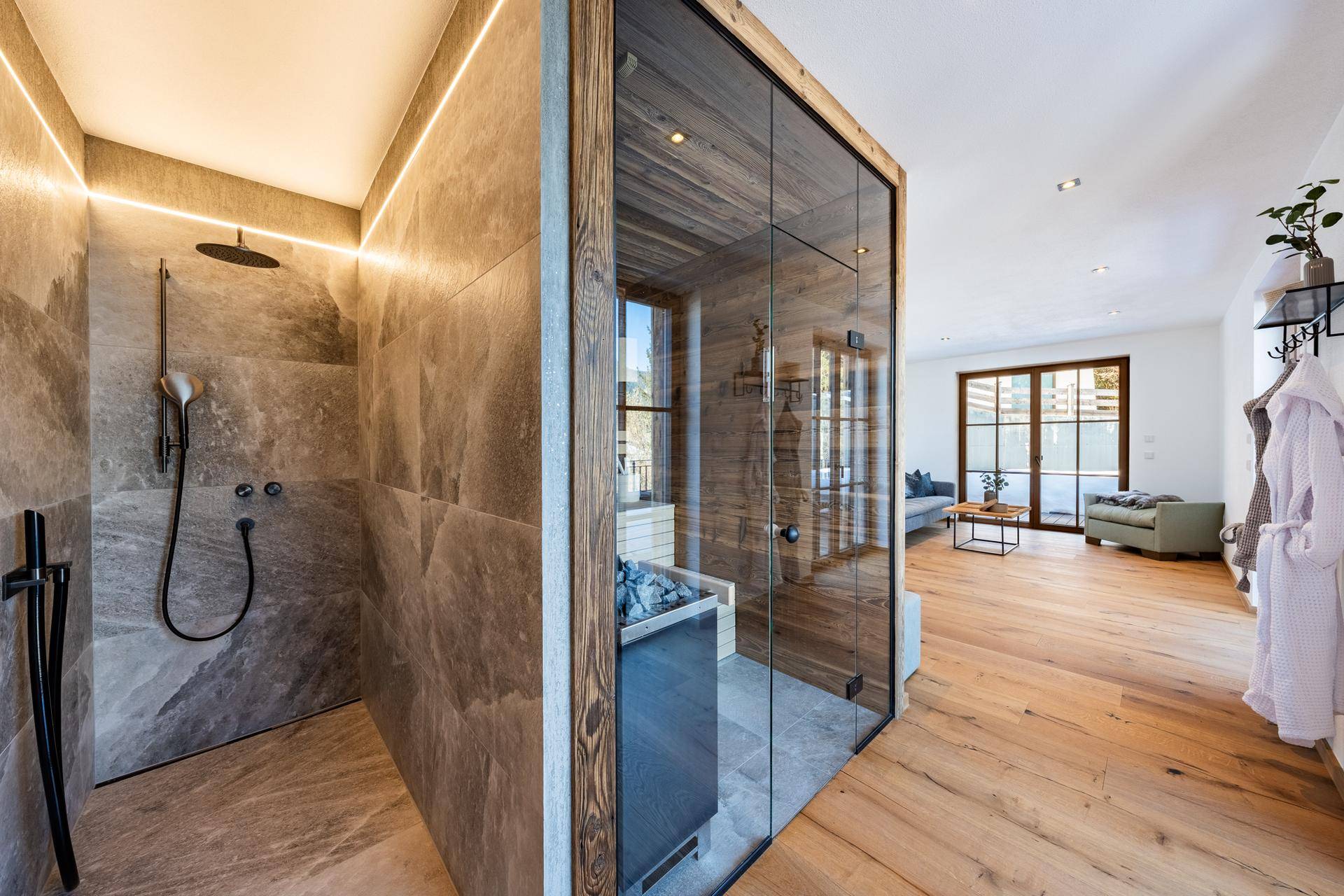 Moderner Wellnessbereich mit großer Dusche, Sauna und Blick ins Grüne.