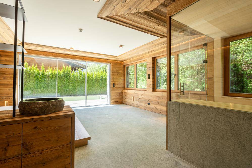 Heller Raum mit Holzwänden, Betonboden und Zugang zu einem privaten Außenbereich.