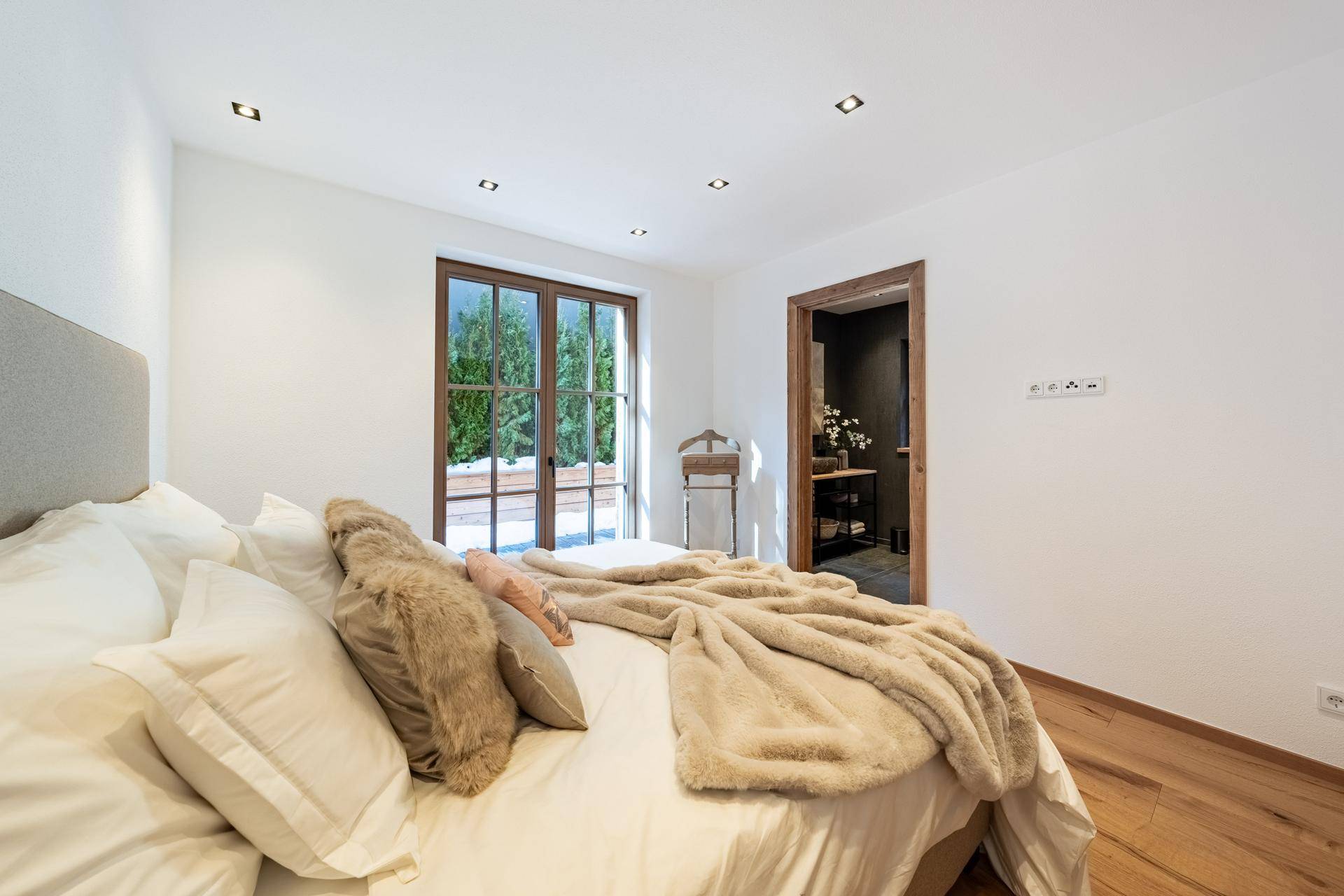 Gemütliches Schlafzimmer mit Holzboden und Fenster, das viel natürliches Licht hereinlässt.
