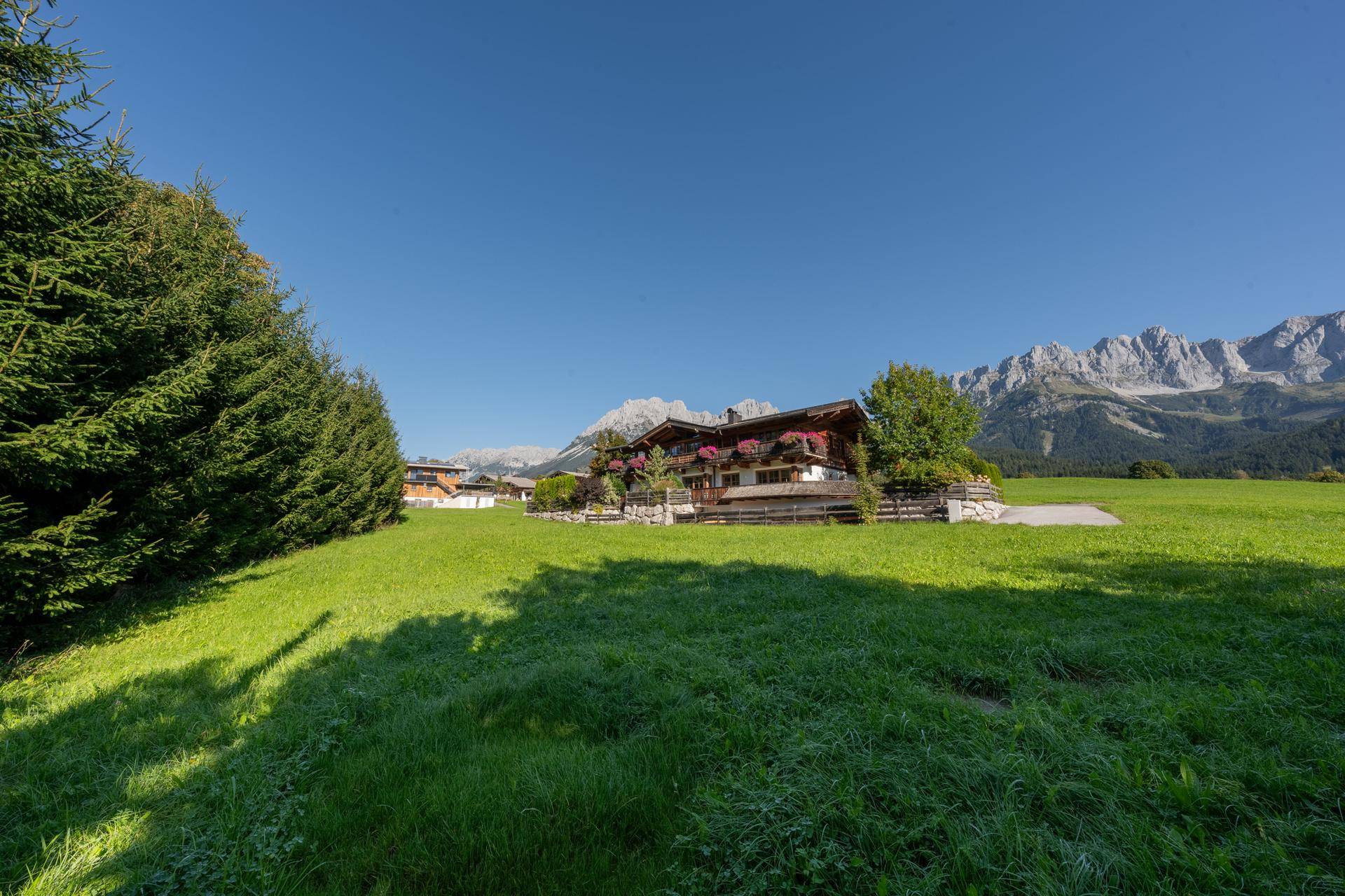 Charmantes Haus in idyllischer Lage, umgeben von weiten grünen Wiesen und beeindruckendem Bergpanorama.