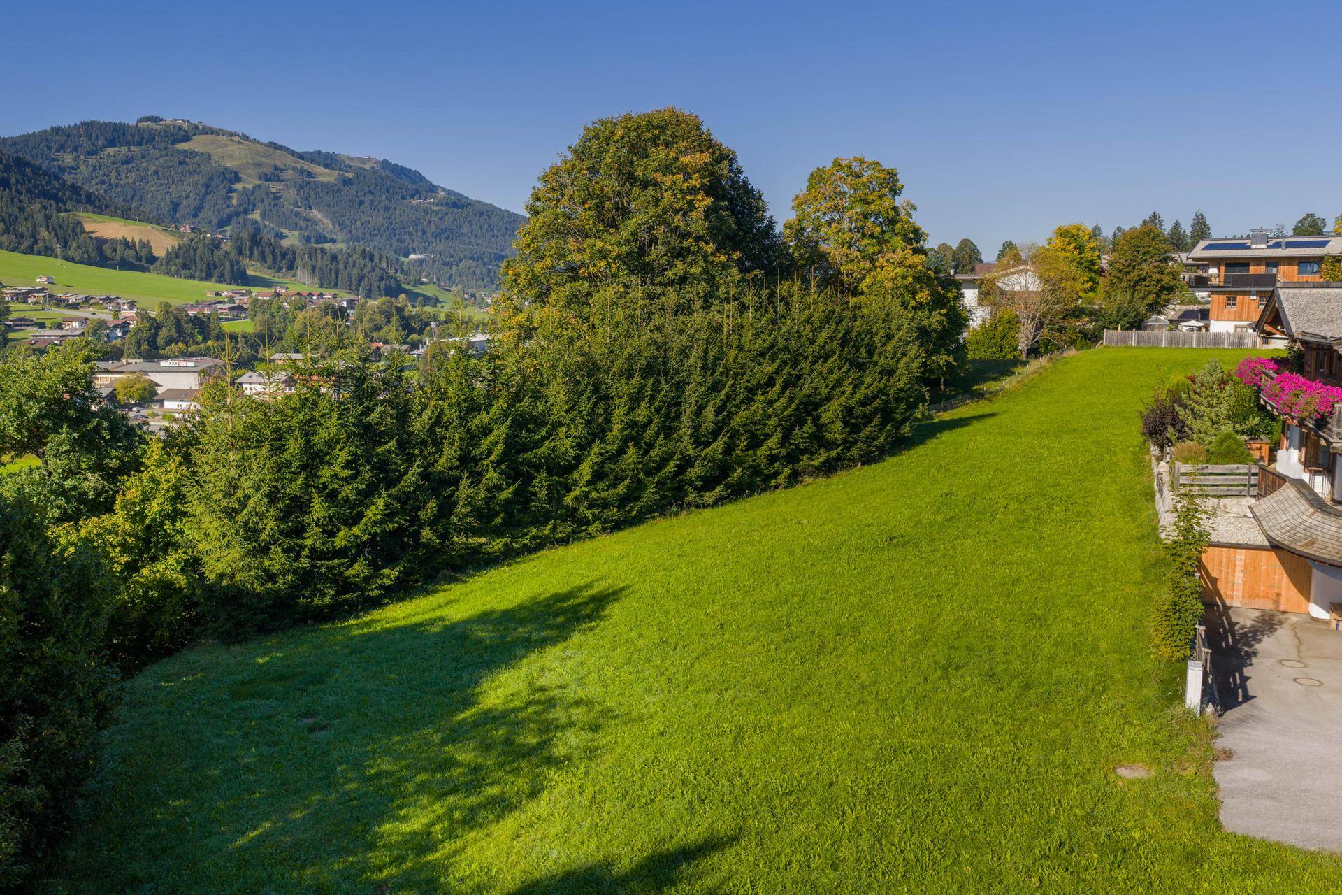 Blick auf die grüne Hanglage des Grundstücks mit Fernsicht auf eine malerische Ortschaft in der Ferne.