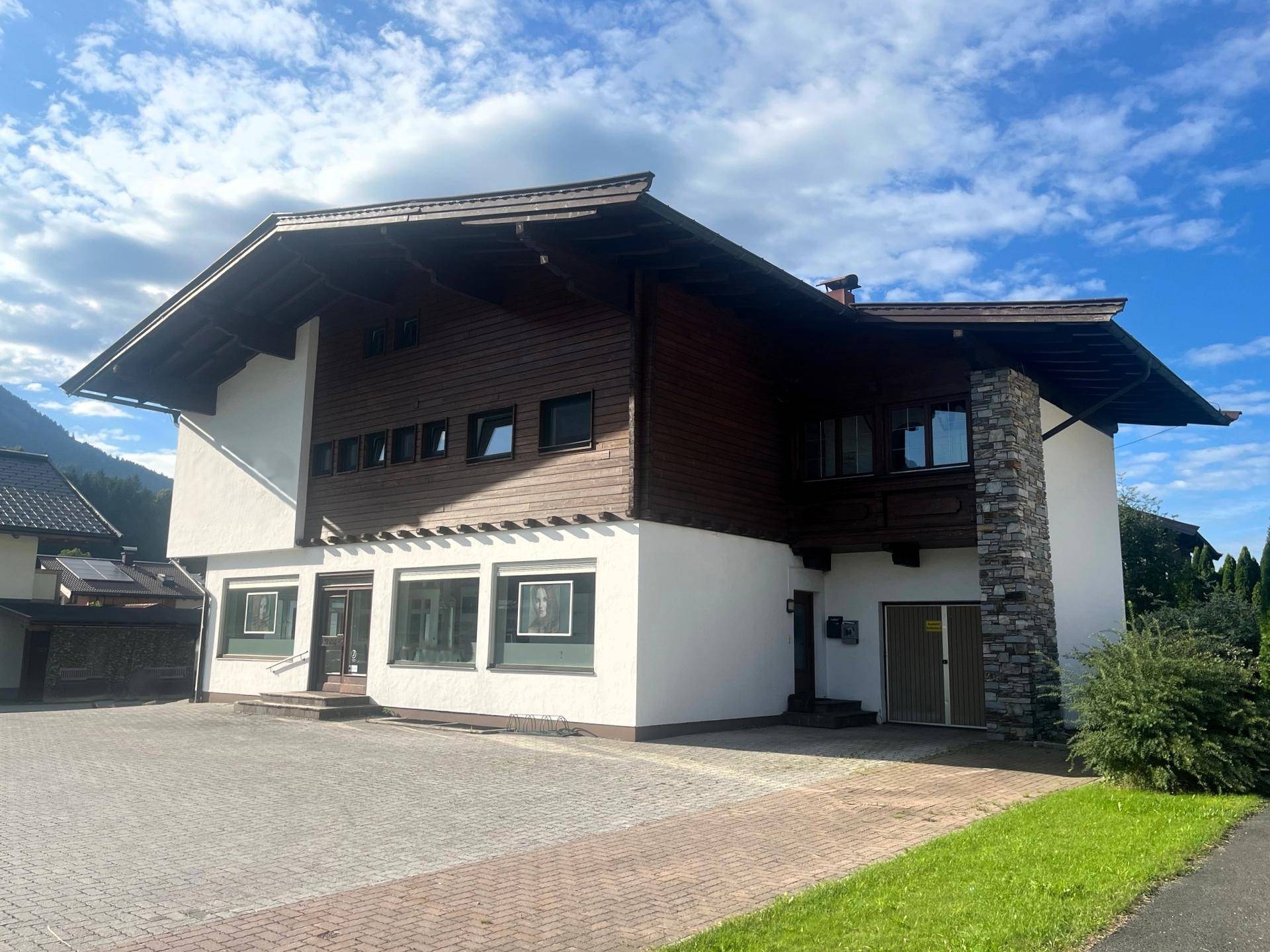 Gebäude im alpinen Stil mit Holzverkleidung und Steinakzenten, umgeben von Berglandschaft.