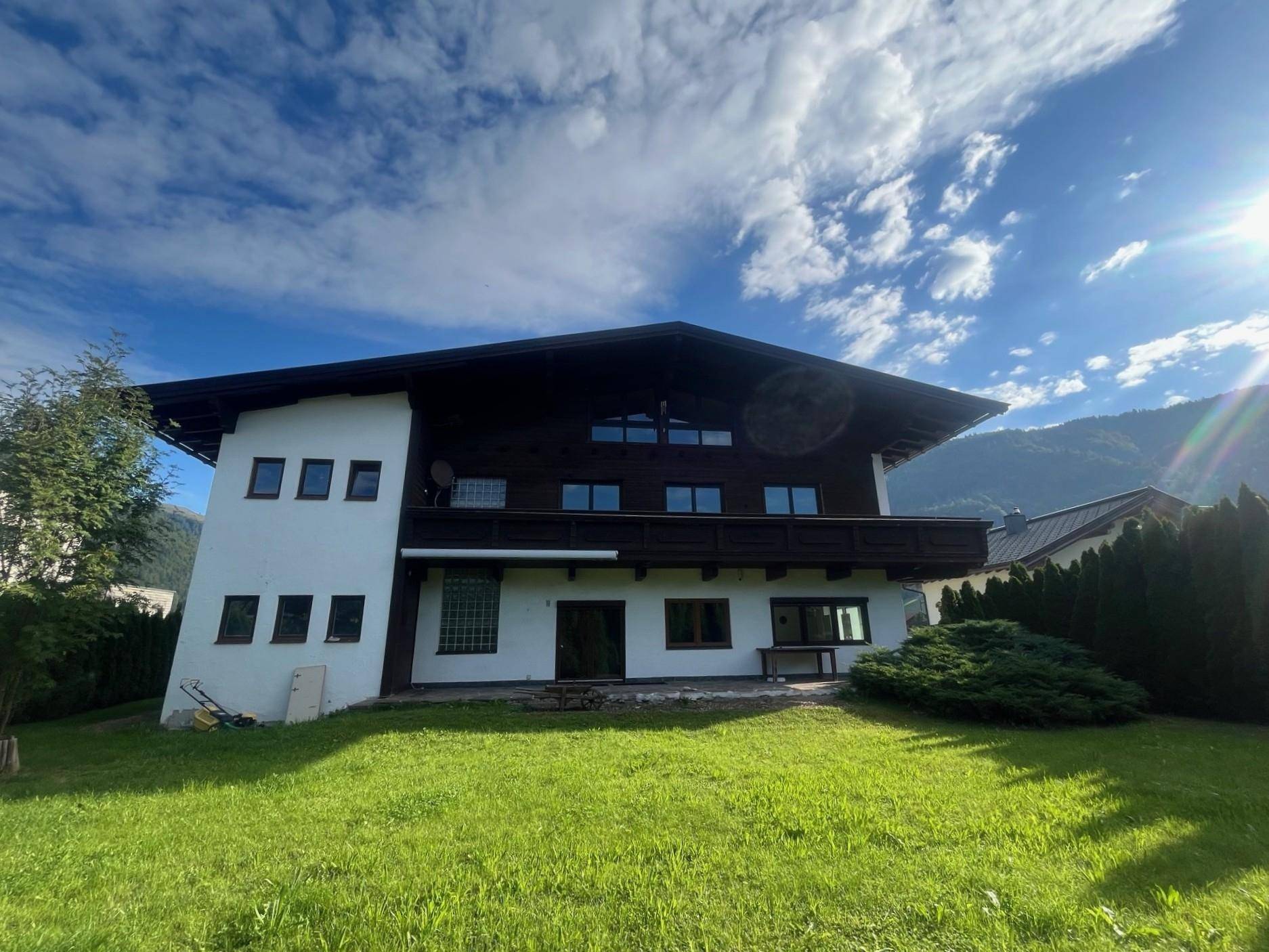 Alpines Wohnhaus mit gepflegtem Garten und weitem Blick auf die umliegende Berglandschaft.