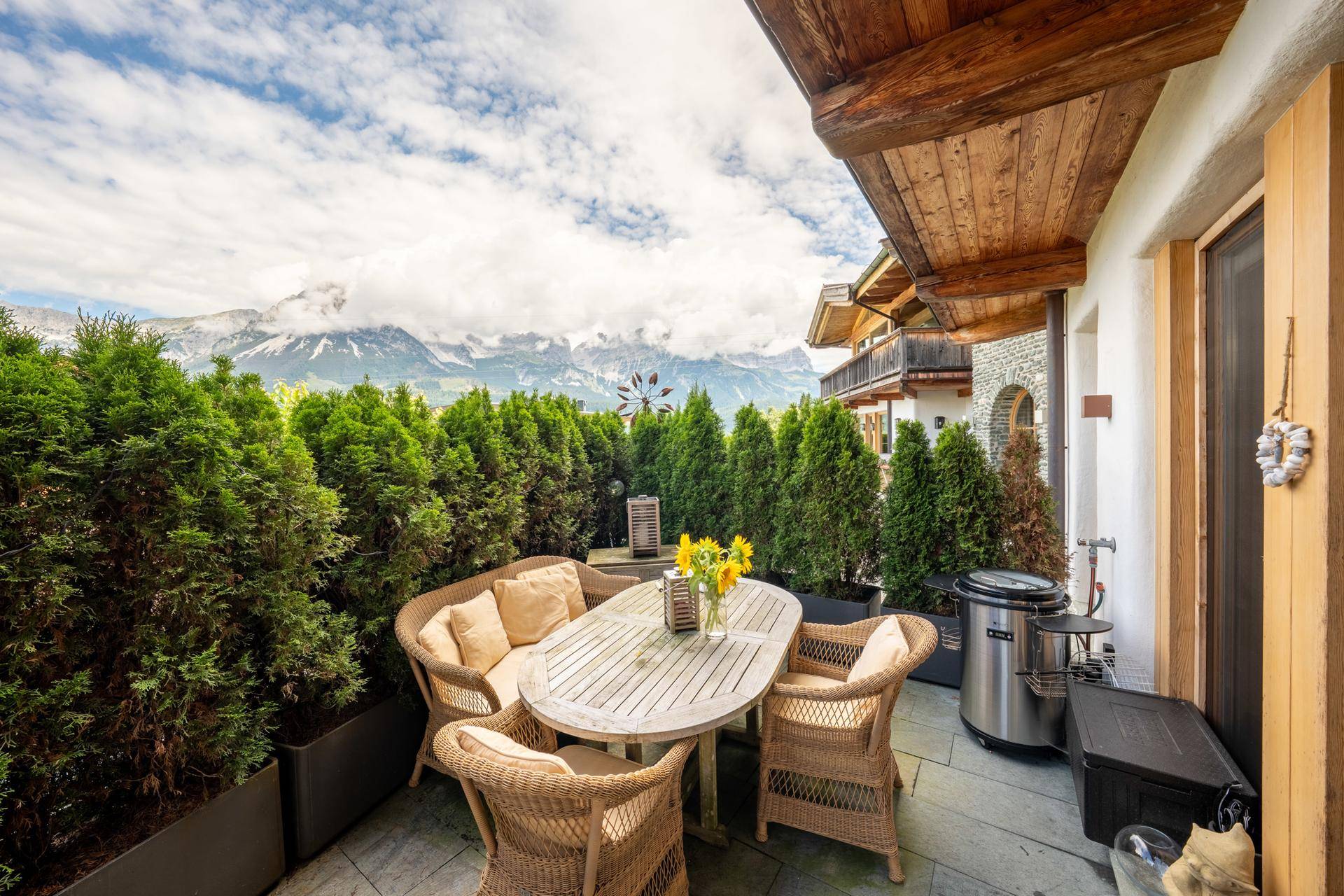Möblierte Terrasse mit Esstisch, Pflanzen und atemberaubendem Panoramablick auf die Berge.