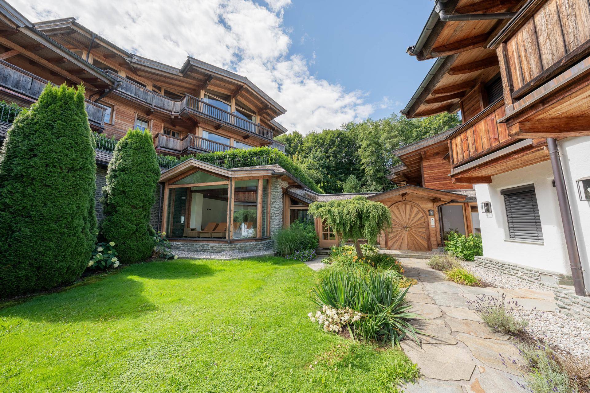 Anwesen im Chalet-Stil mit üppigem Grün, Steinweg und traditioneller Holzarchitektur.