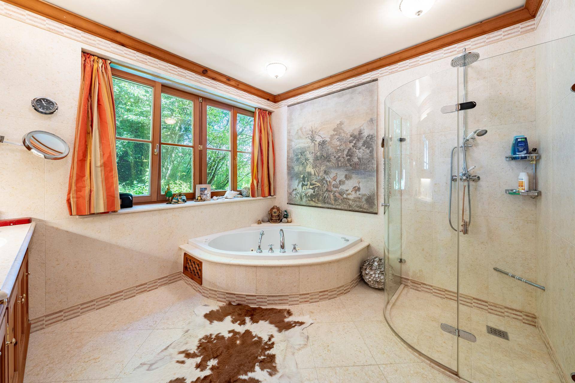 Helles Badezimmer mit Eckbadewanne, Glasdusche und Fenster mit Blick ins Grüne.