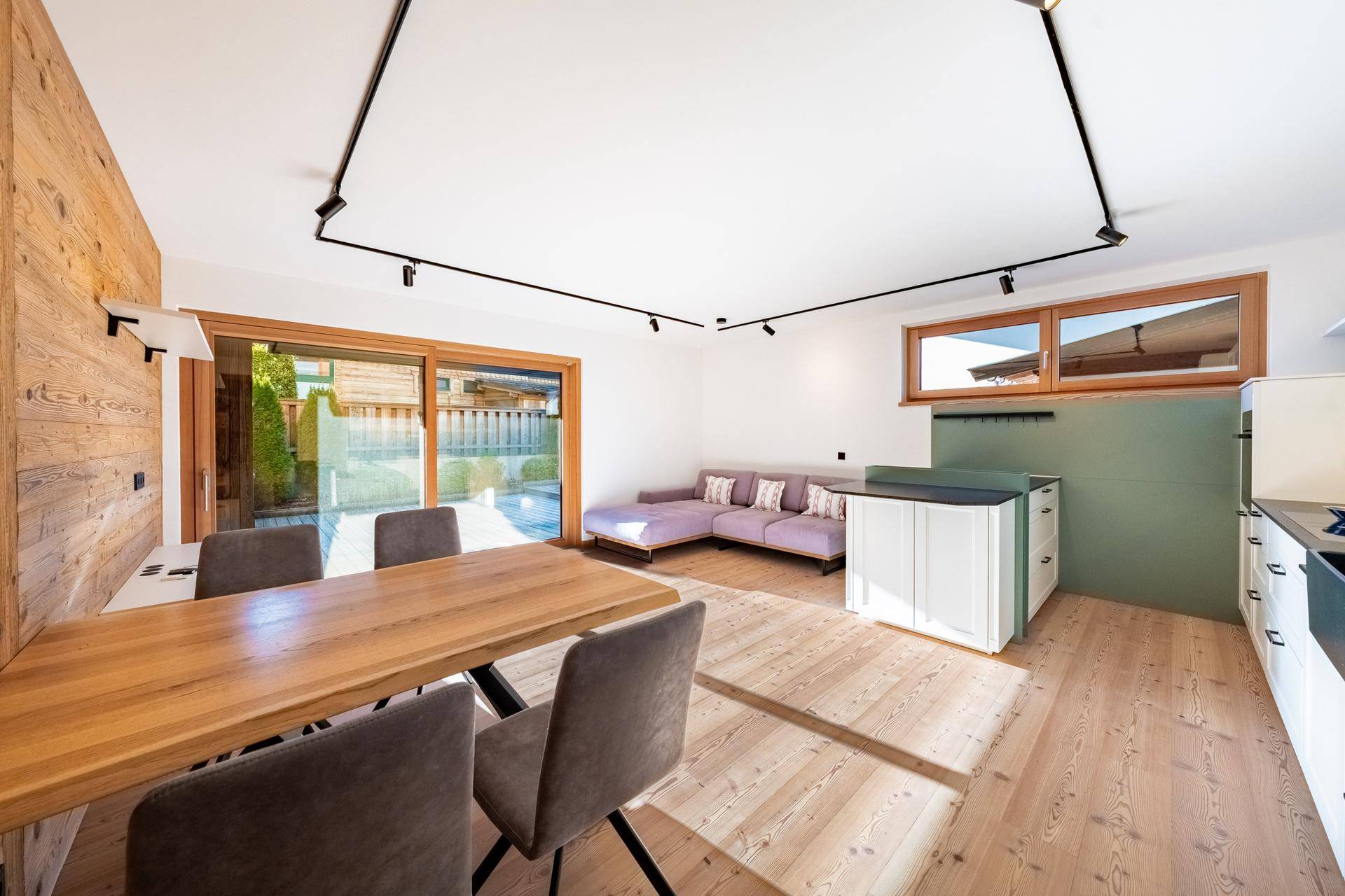 Lichtdurchfluteter Wohn-Essbereich mit Holzboden, Zugang zur Terrasse und moderner offener Küche.