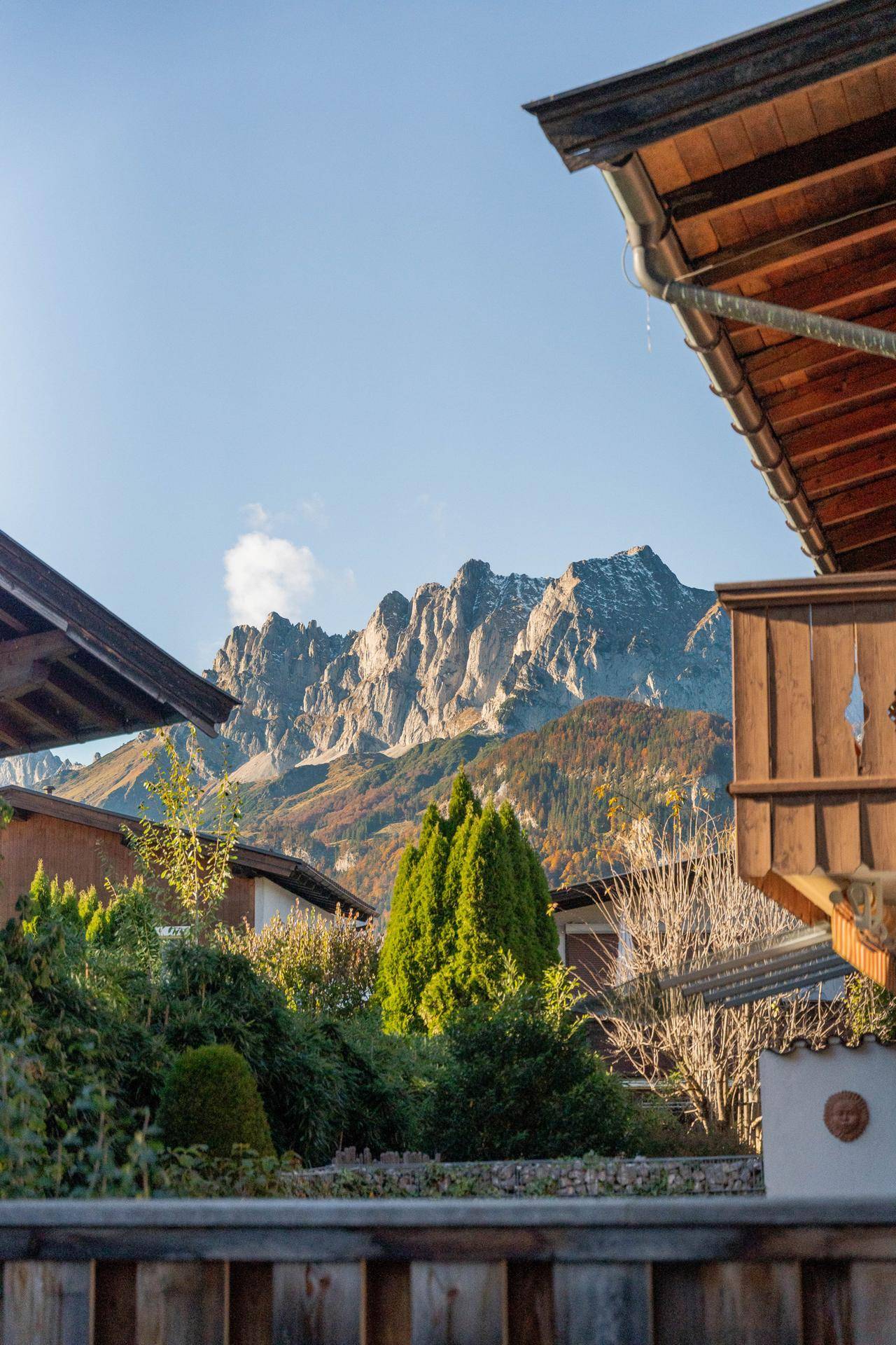 Malerischer Blick auf die majestätischen Berge über den Dächern und grünen Bäumen.