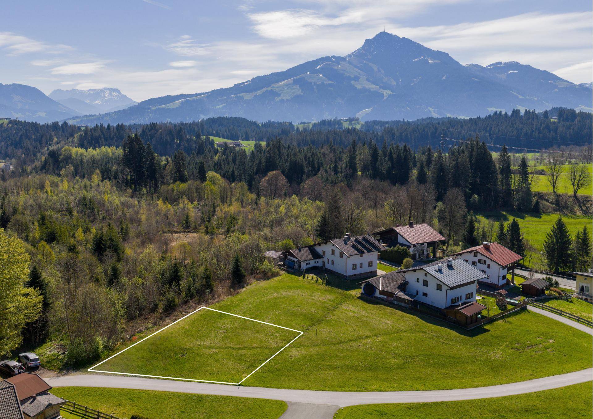 Luftaufnahme eines Baugrundstücks in ländlicher Umgebung mit weitem Blick auf die Berge.
