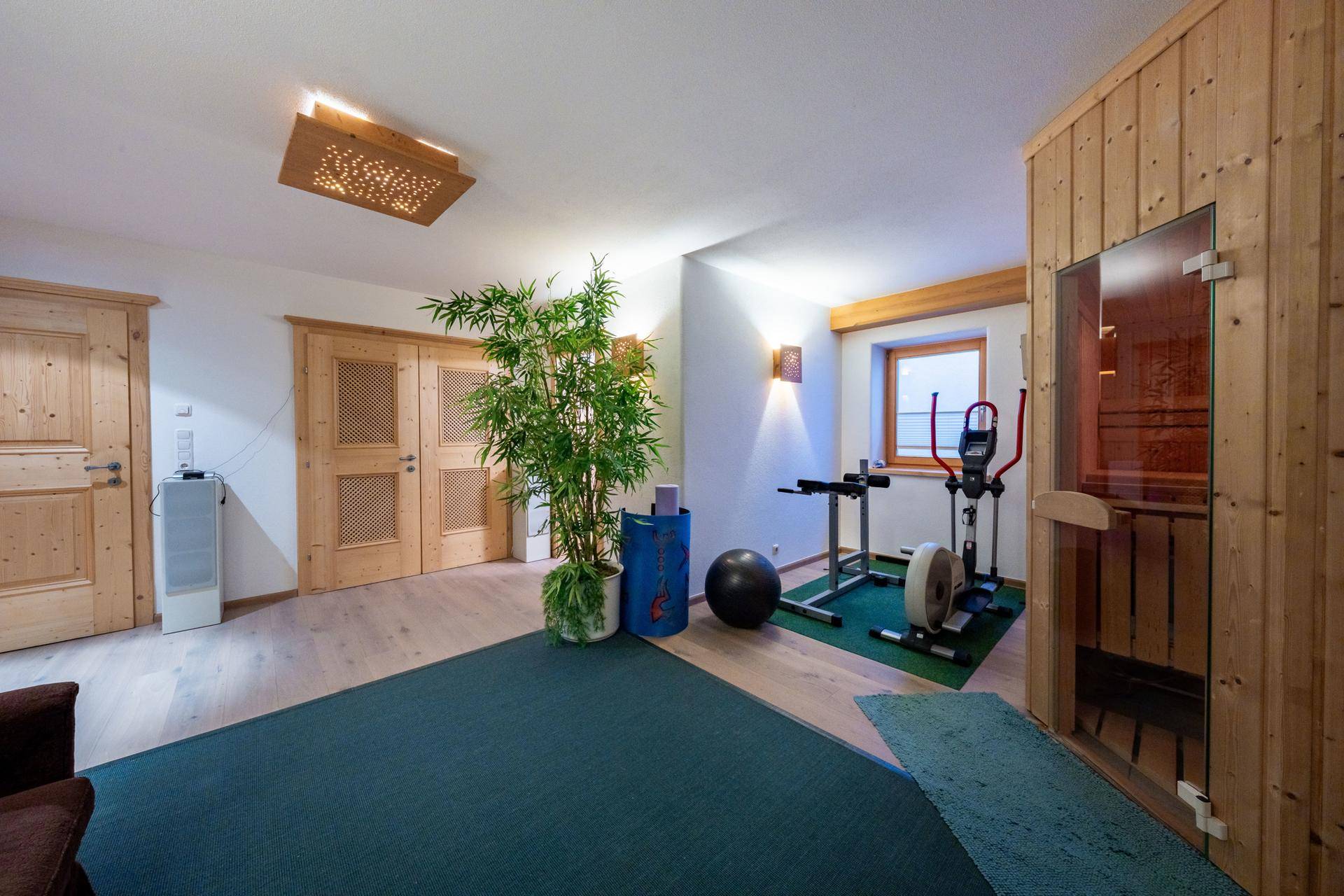 Fitnessbereich mit Sauna, Trainingsgeräten und Holzelementen für ein gesundes Training.