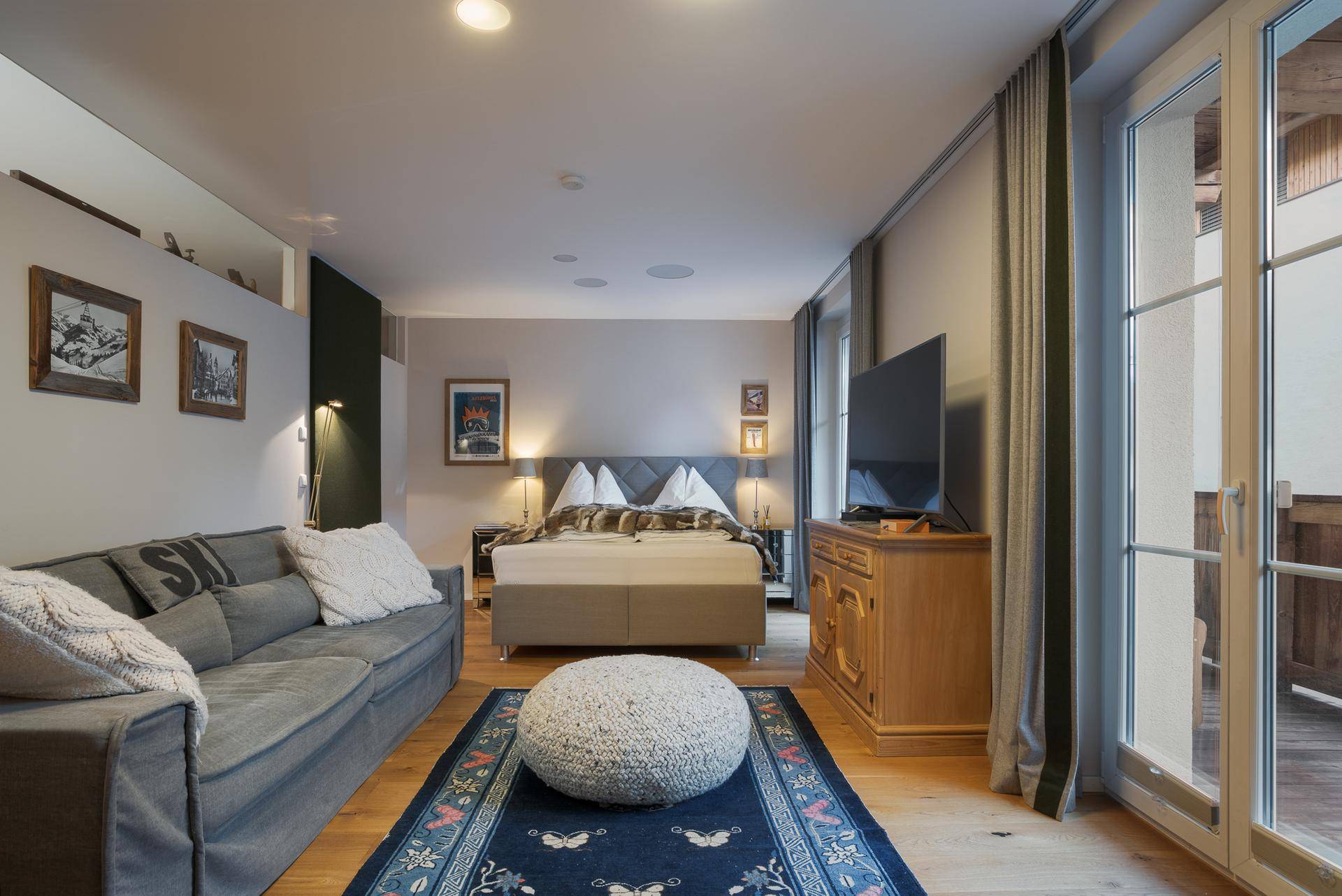 Gemütliches Schlafzimmer mit Doppelbett, Sofa und Holzboden, mit Zugang zu einem Balkon.