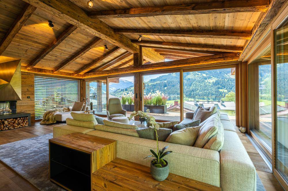 Gemütliches Wohnzimmer mit großem Sofa, Kamin und raumhohen Fenstern mit Bergblick.