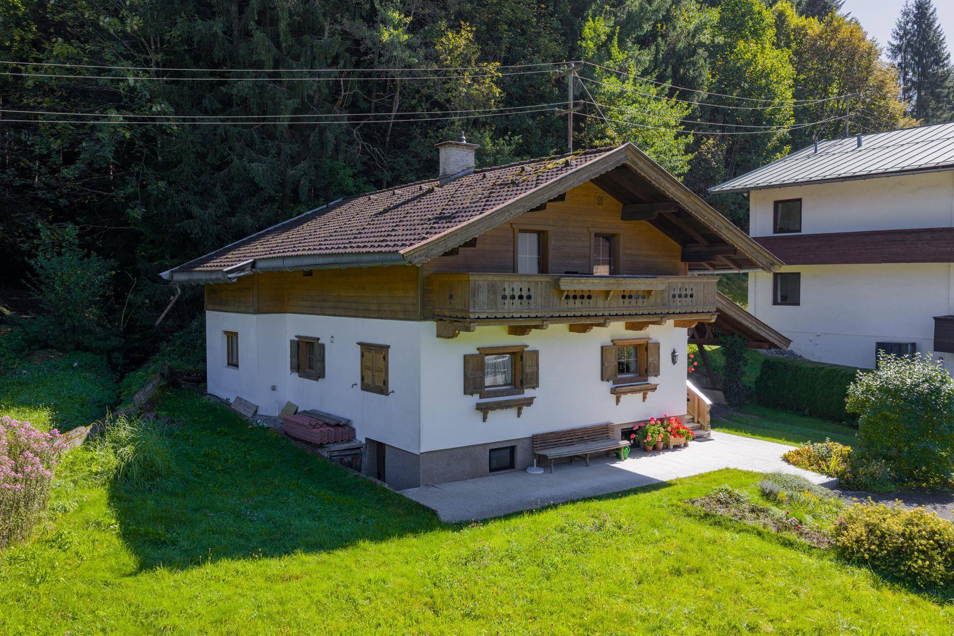 Charmantes Haus im Alpenstil mit Holzbalkon, Fensterläden und gepflegtem Vorgarten.
