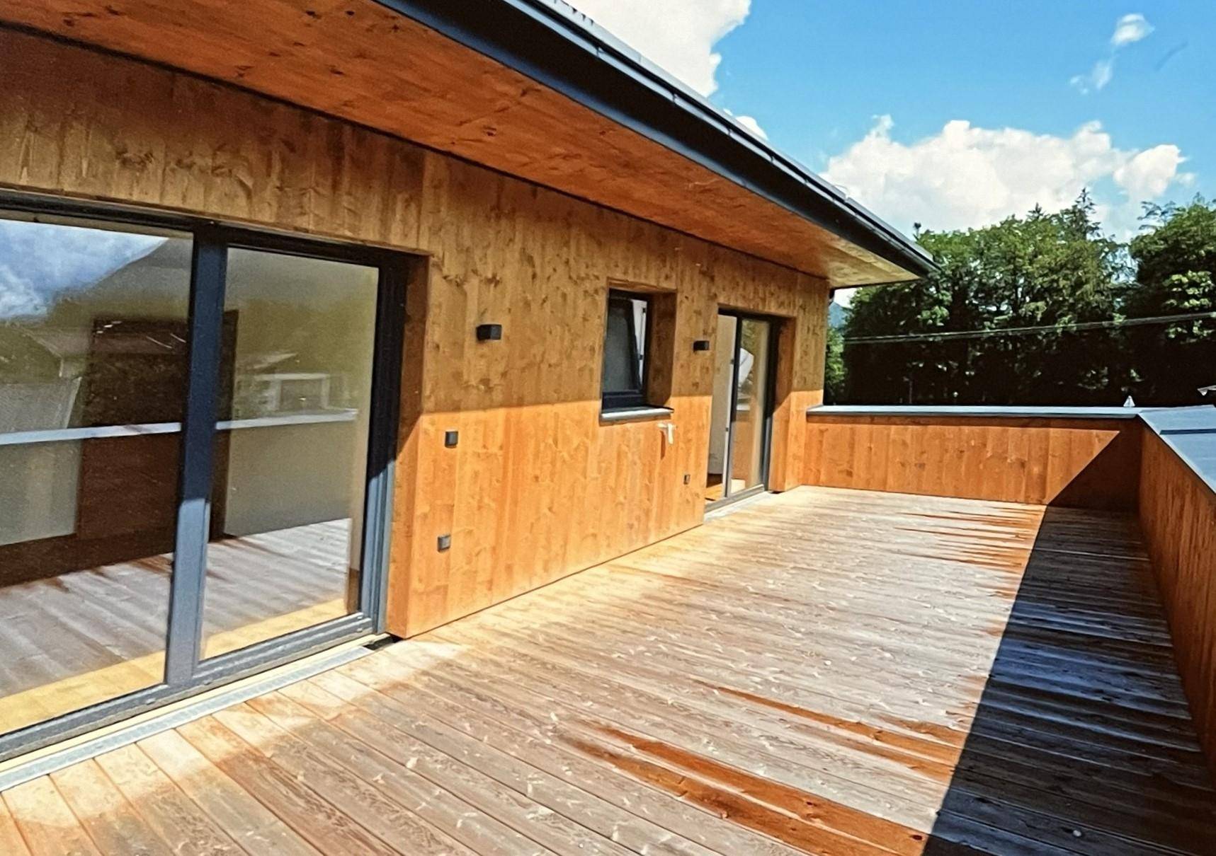Geräumige Holzterrasse mit Schiebetüren und Blick ins Grüne, ideal für Entspannung im Freien.