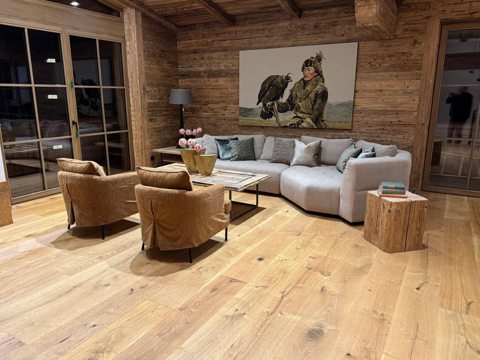 Gemütliches Wohnzimmer im alpinen Stil mit Holzwänden, Ecksofa und Zugang zur Terrasse.