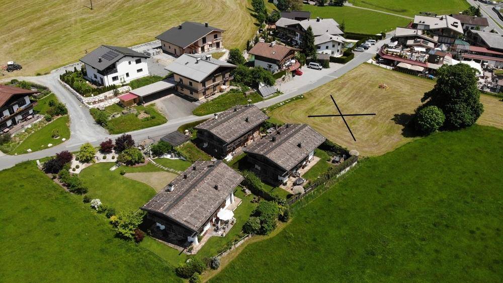 Luftaufnahme von mehreren Häusern mit Gärten und umliegenden grünen Feldern in einer ländlichen Umgebung.