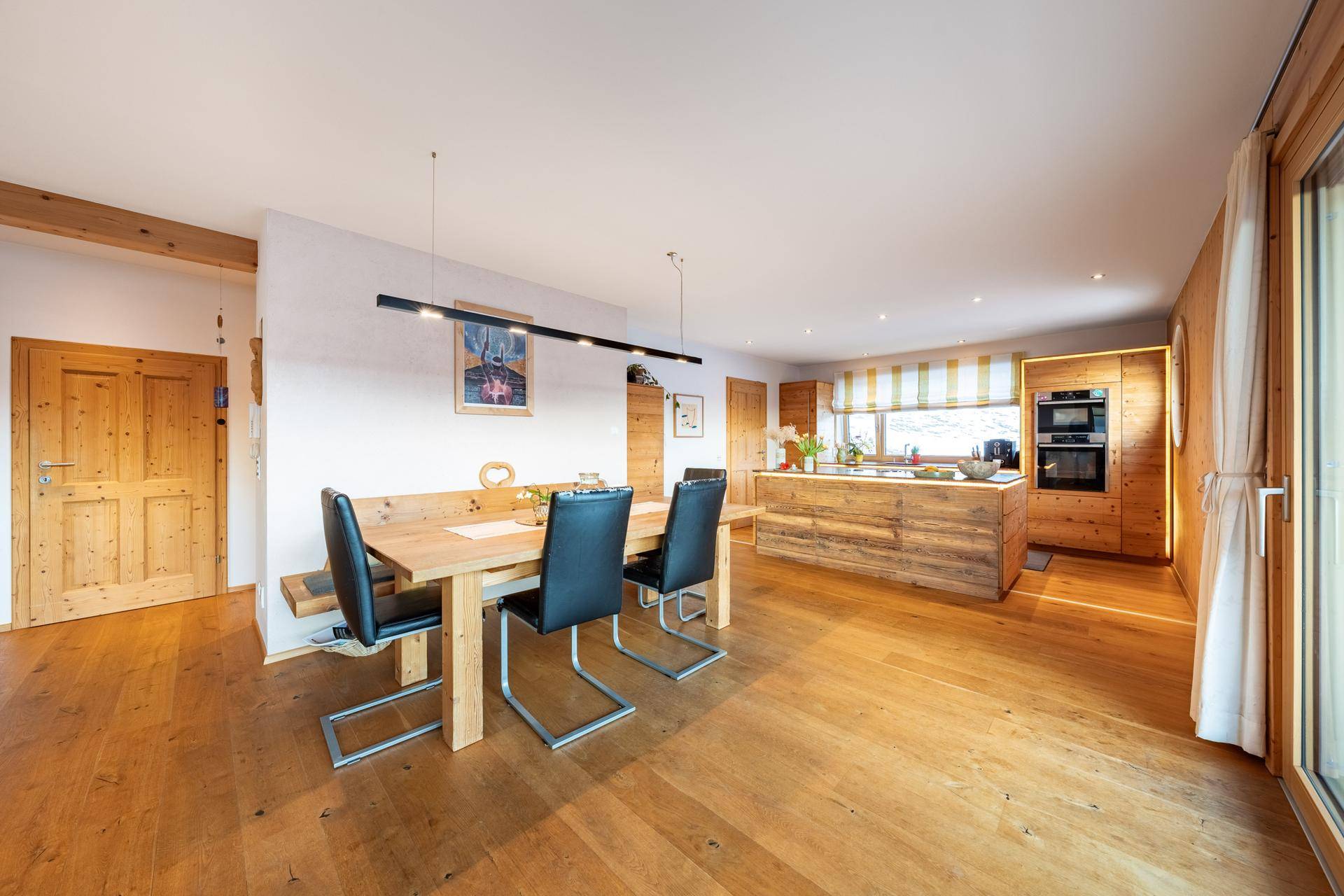Offener Wohn-Essbereich mit Holzboden, Holzküche und Esstisch in modernem Landhausstil.