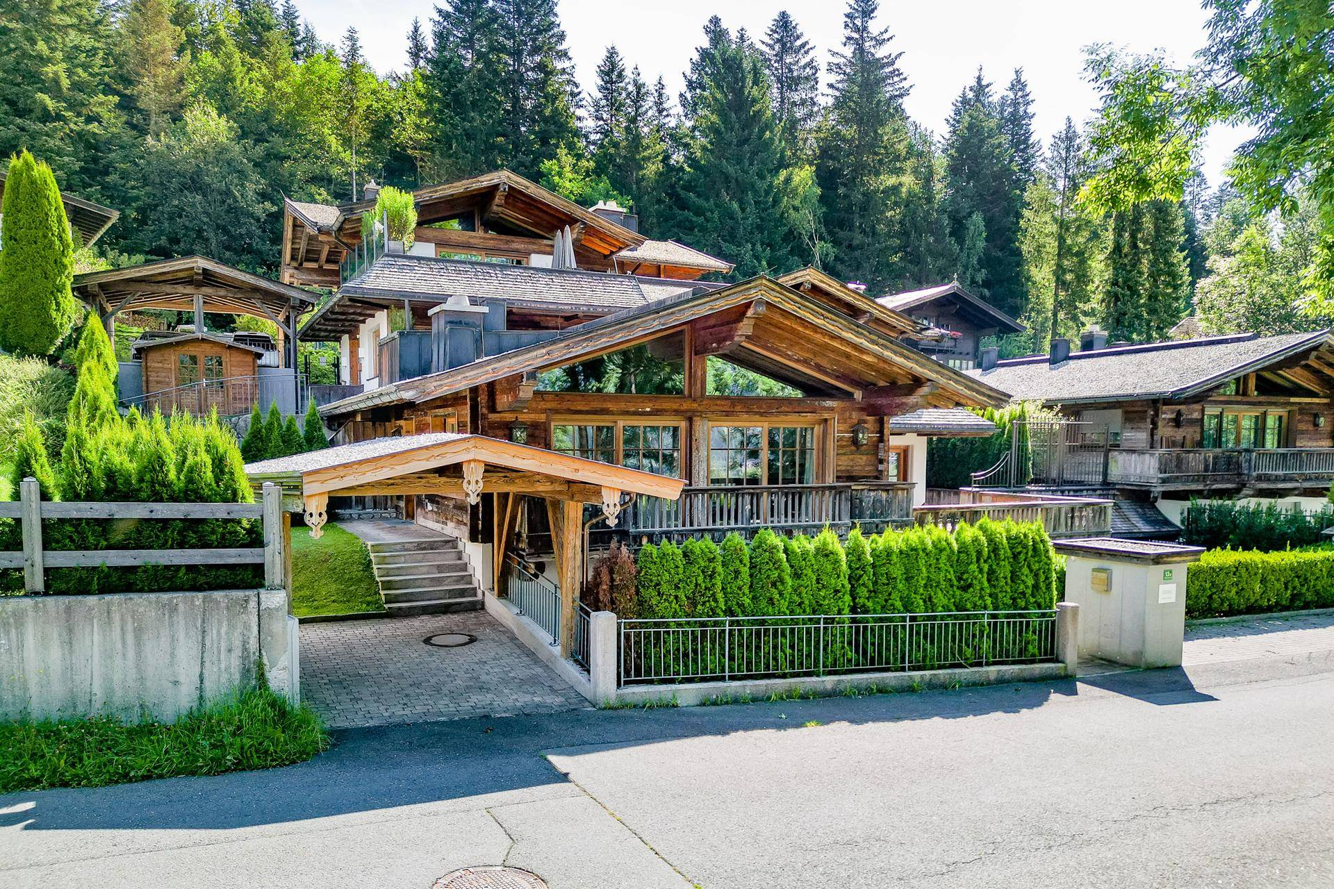 Breitere Ansicht des alpinen Holzchalets mit Carport und umgebender Natur.