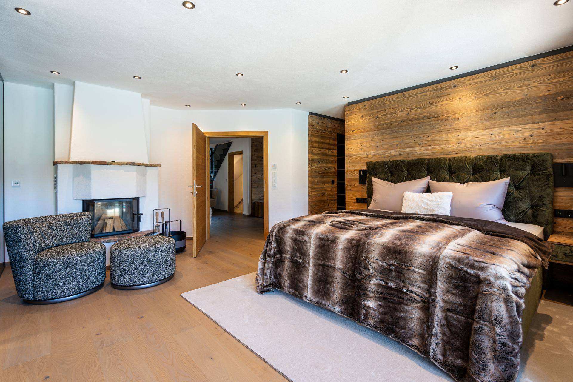 Gemütliches Schlafzimmer mit Kamin, Holzwand und bequemen Sitzgelegenheiten.