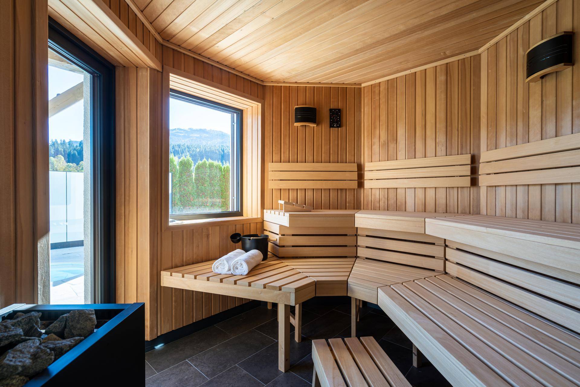 Geräumige Holzsauna mit Sitzbänken und Blick auf die umliegende Natur.