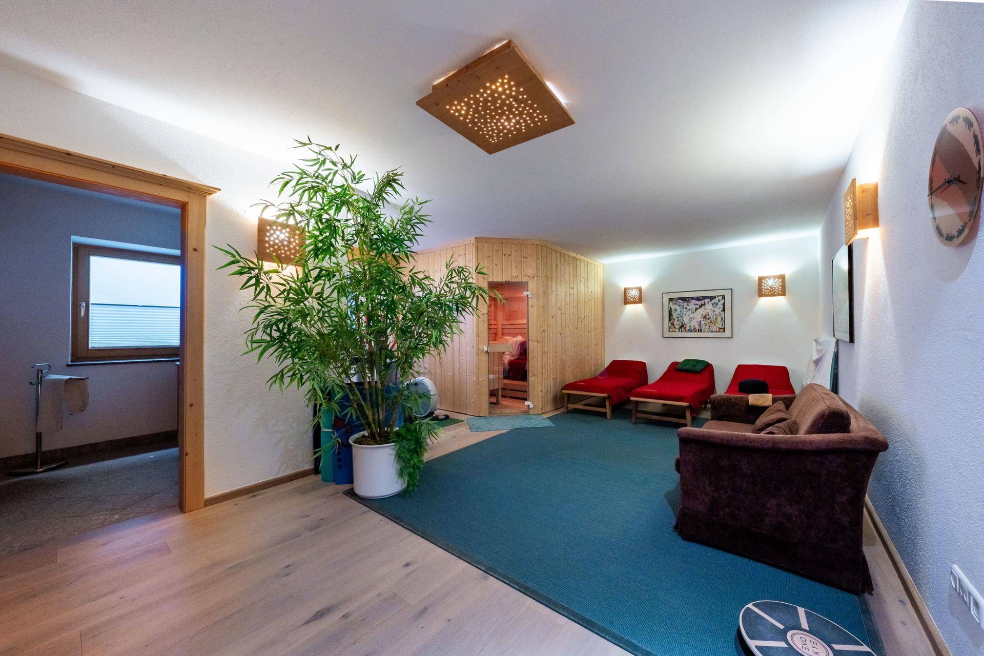 Entspannungsbereich mit Sauna, Liegen und Blick ins Freie durch ein Fenster.