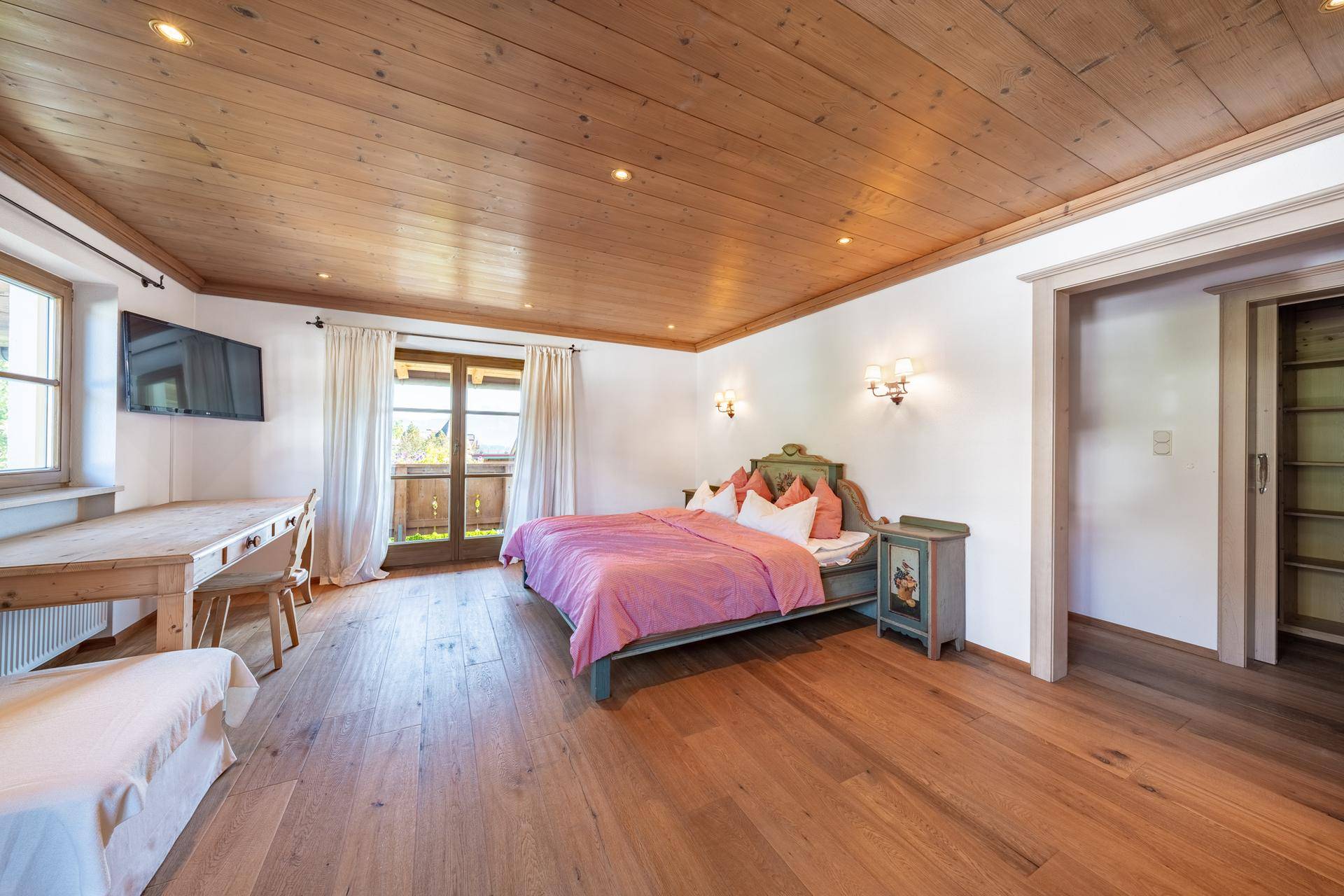 Geräumiges Schlafzimmer mit Holzboden, traditionellem Bett und Zugang zu einem Balkon mit Bergblick.