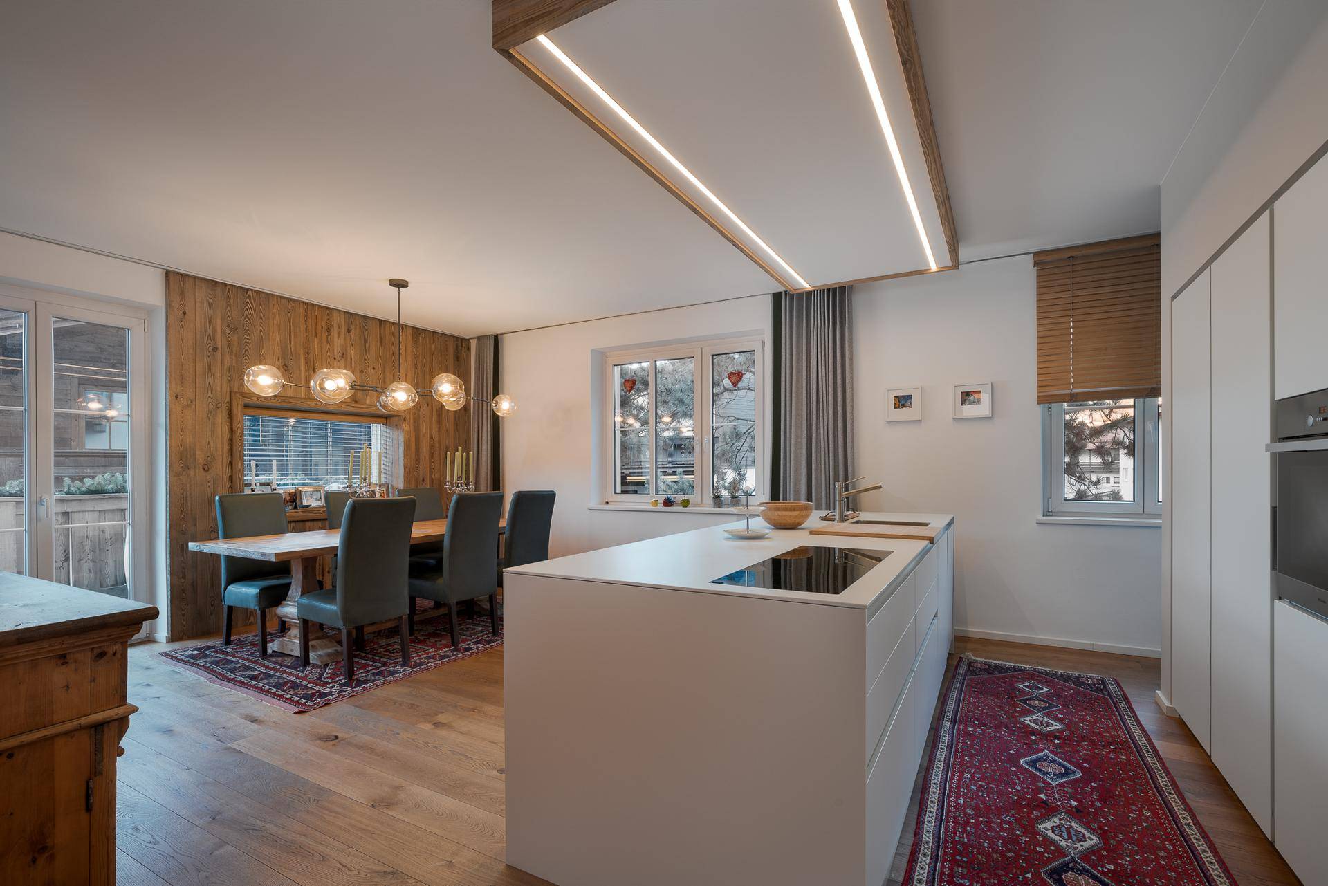 Moderne Küche mit Kochinsel und Essbereich, kombiniert mit rustikalen Holzelementen und Holzboden.