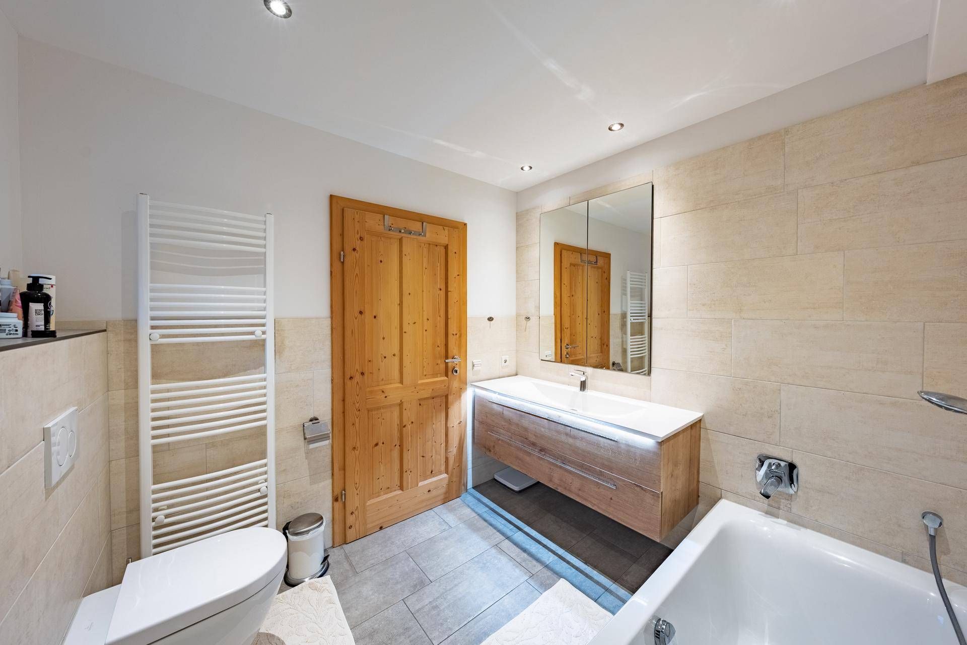 Modernes Badezimmer mit Badewanne, WC, Einzelwaschbecken und beheiztem Handtuchhalter.