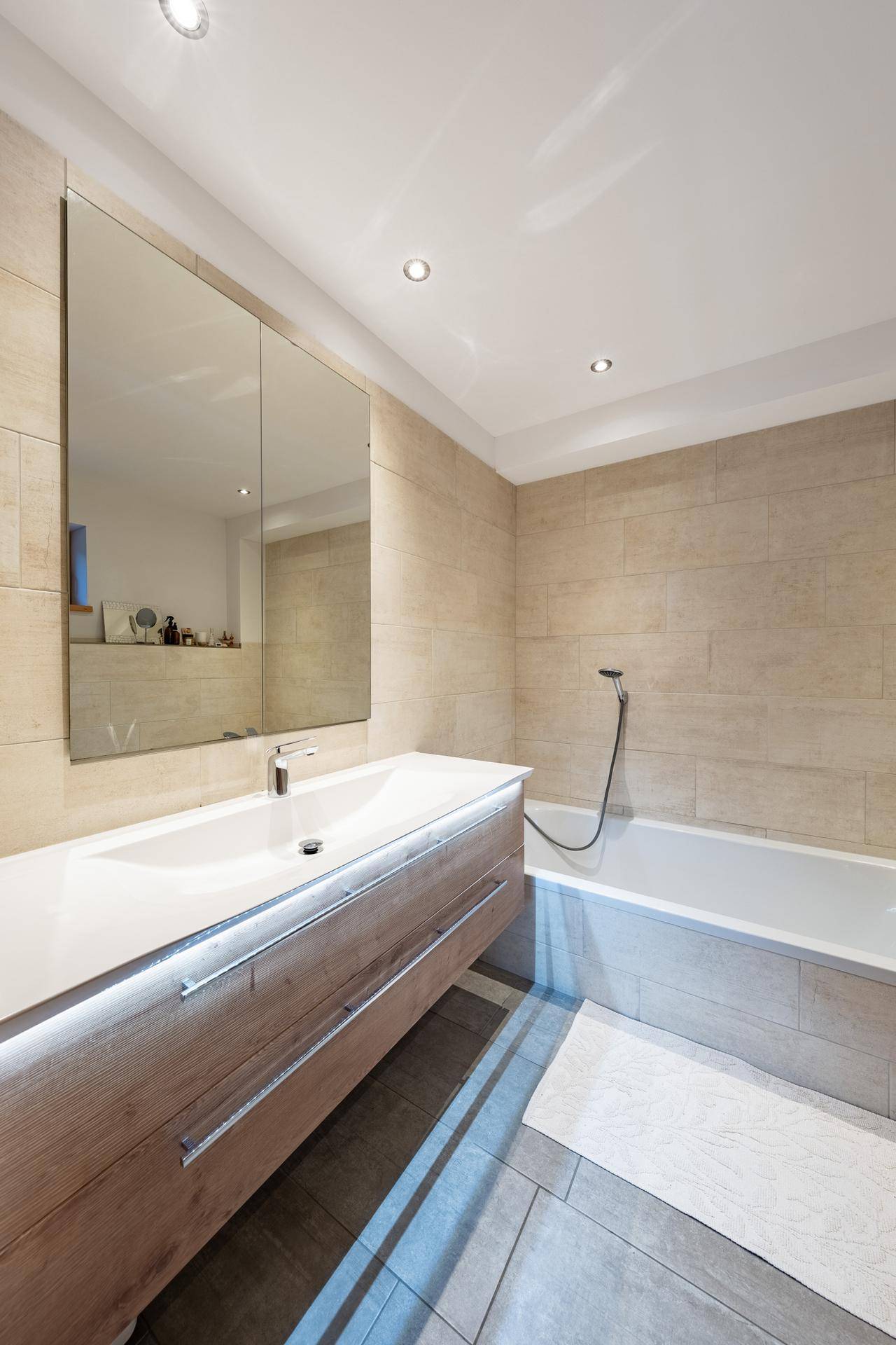 Elegantes Badezimmer mit Badewanne, modernem Waschtisch und großem Spiegelschrank.