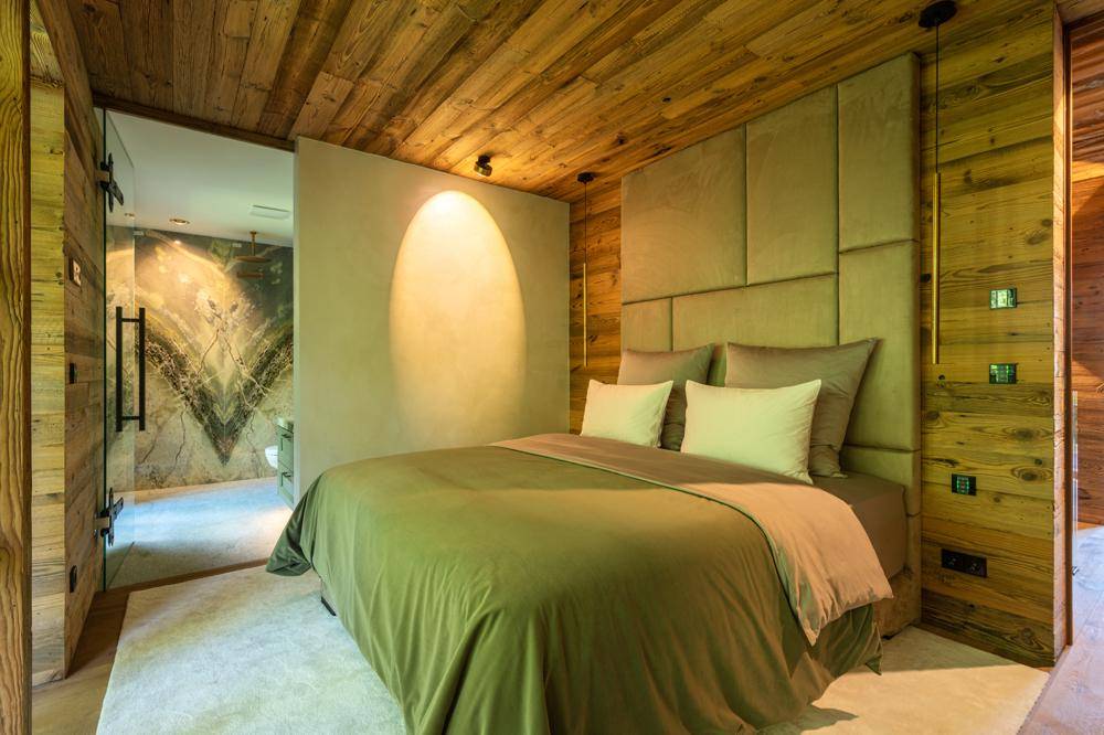 Gemütliches Schlafzimmer mit Holzwänden und direktem Zugang zu einem luxuriösen Badezimmer.