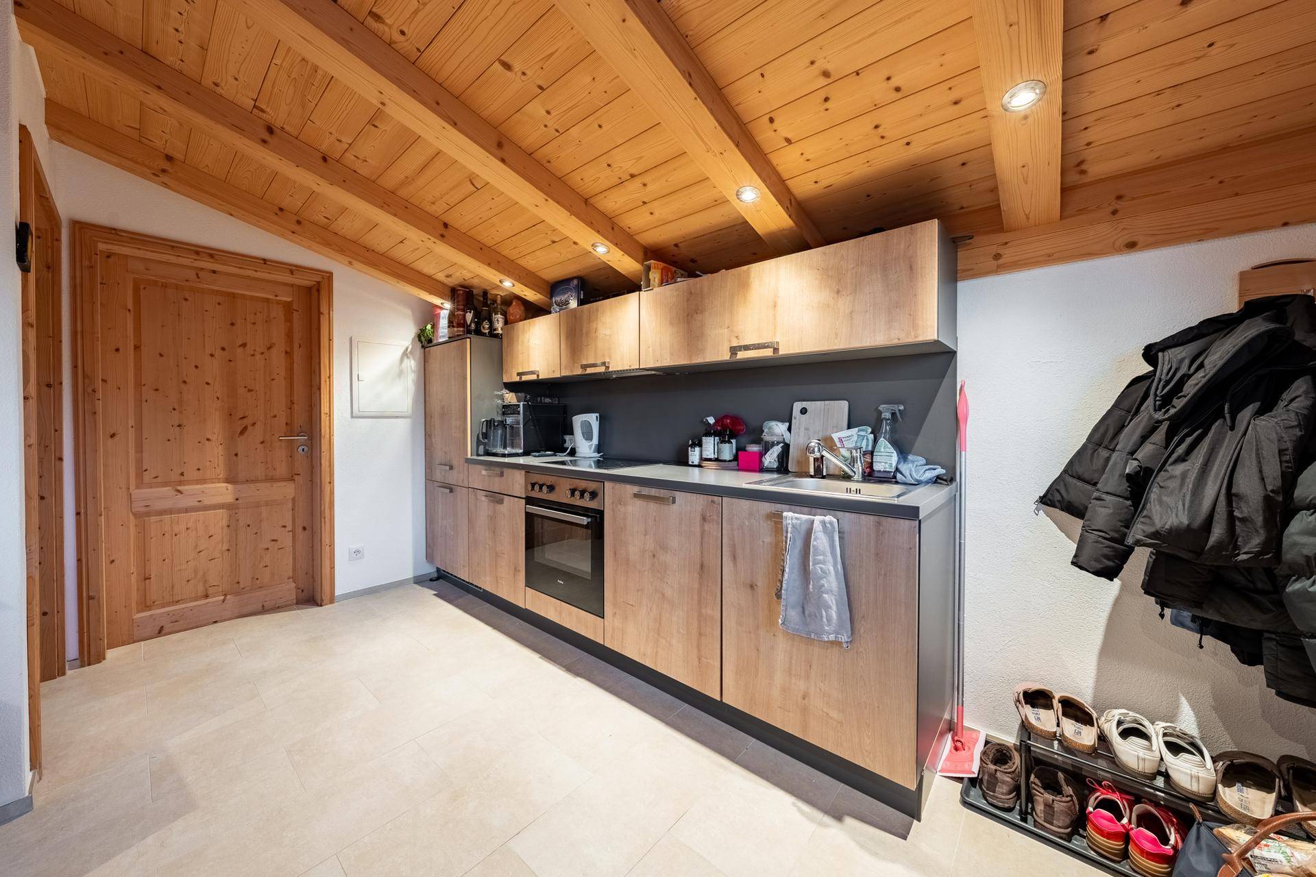 Funktionale Küchenzeile im Dachgeschoss mit Holzdecke und integrierten Geräten.