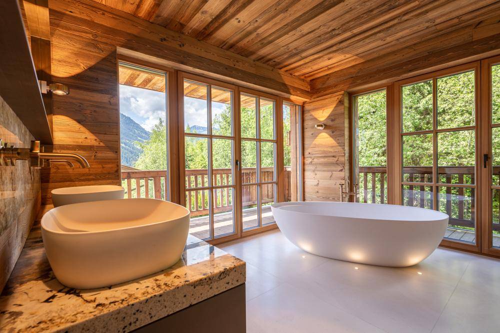 Luxuriöses Badezimmer mit freistehender Badewanne, Doppelwaschbecken und Panoramablick auf die Berge.