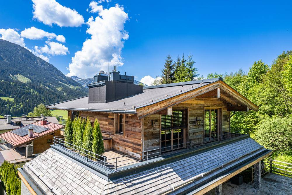 Dachansicht des modernen Holzchalets mit Flachdach und umlaufender Terrasse in den Bergen.